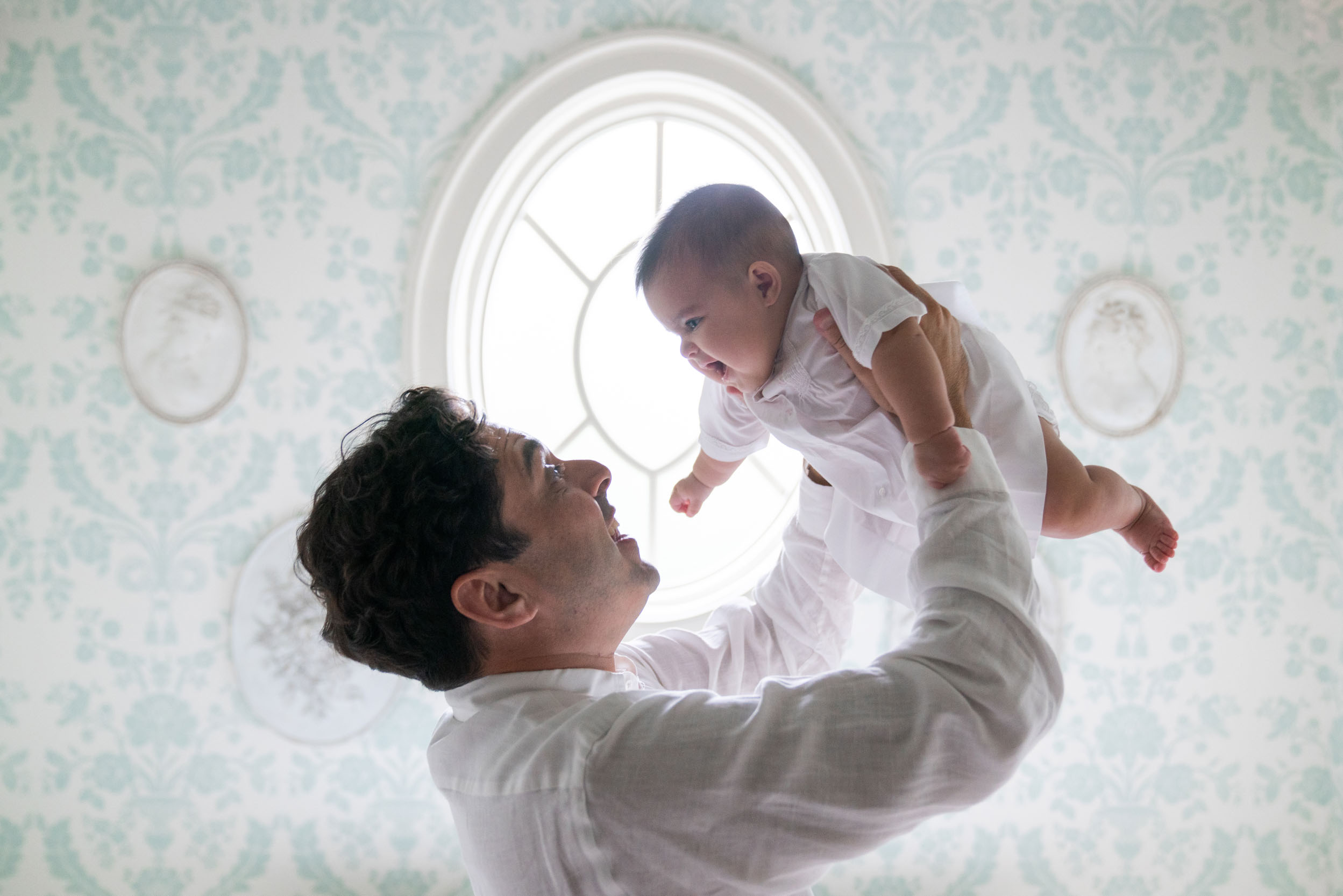 Father holding baby smiling and laughing with beautiful lighting