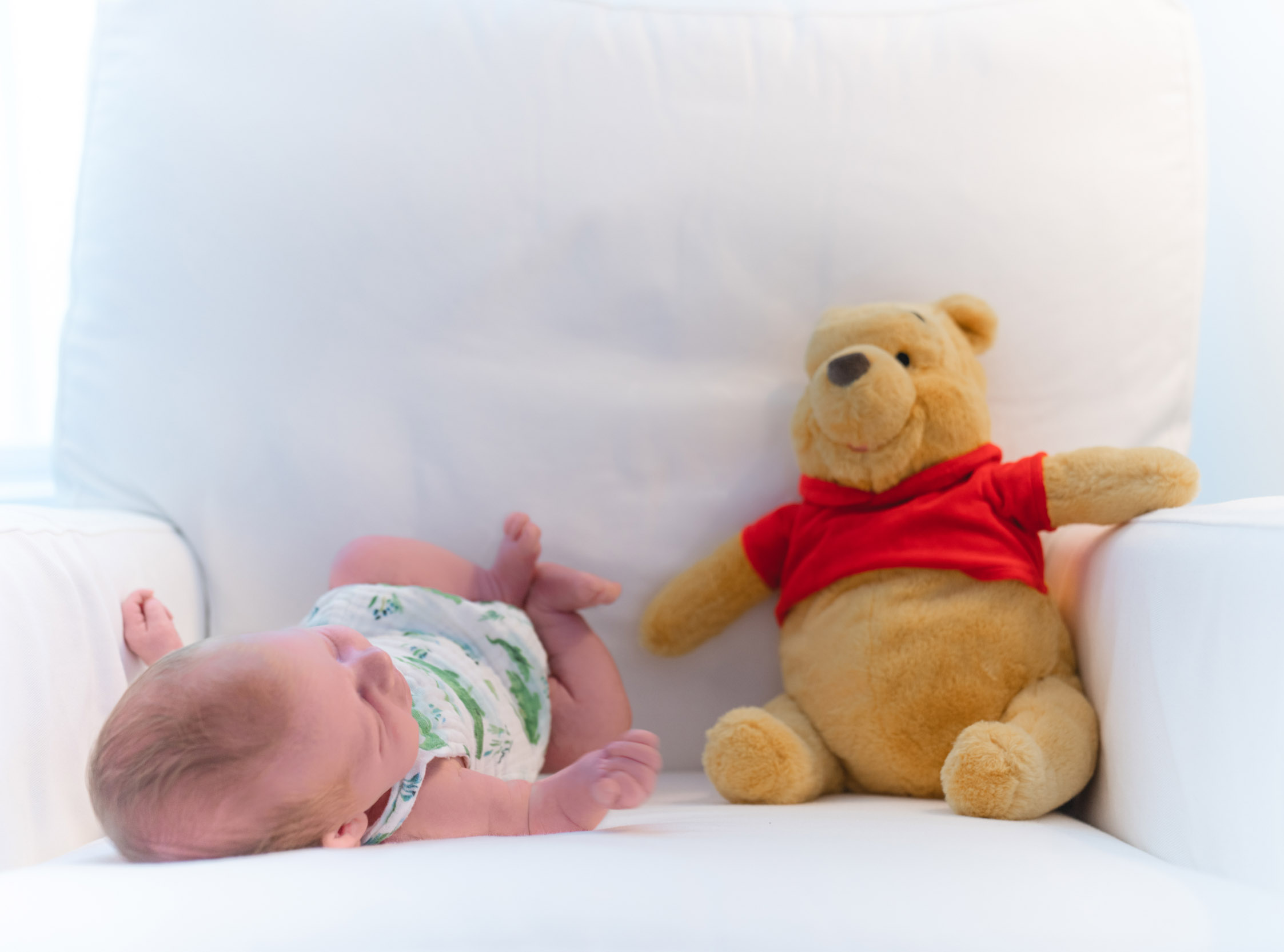 Baby laying with winnie the pooh doll with beautiful lighting