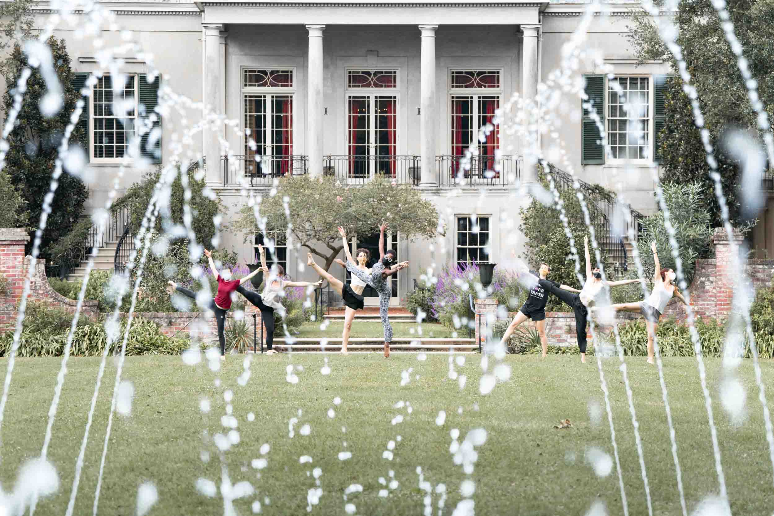 Dancers performing in front of a New Orleans mansion with fountain in foreground