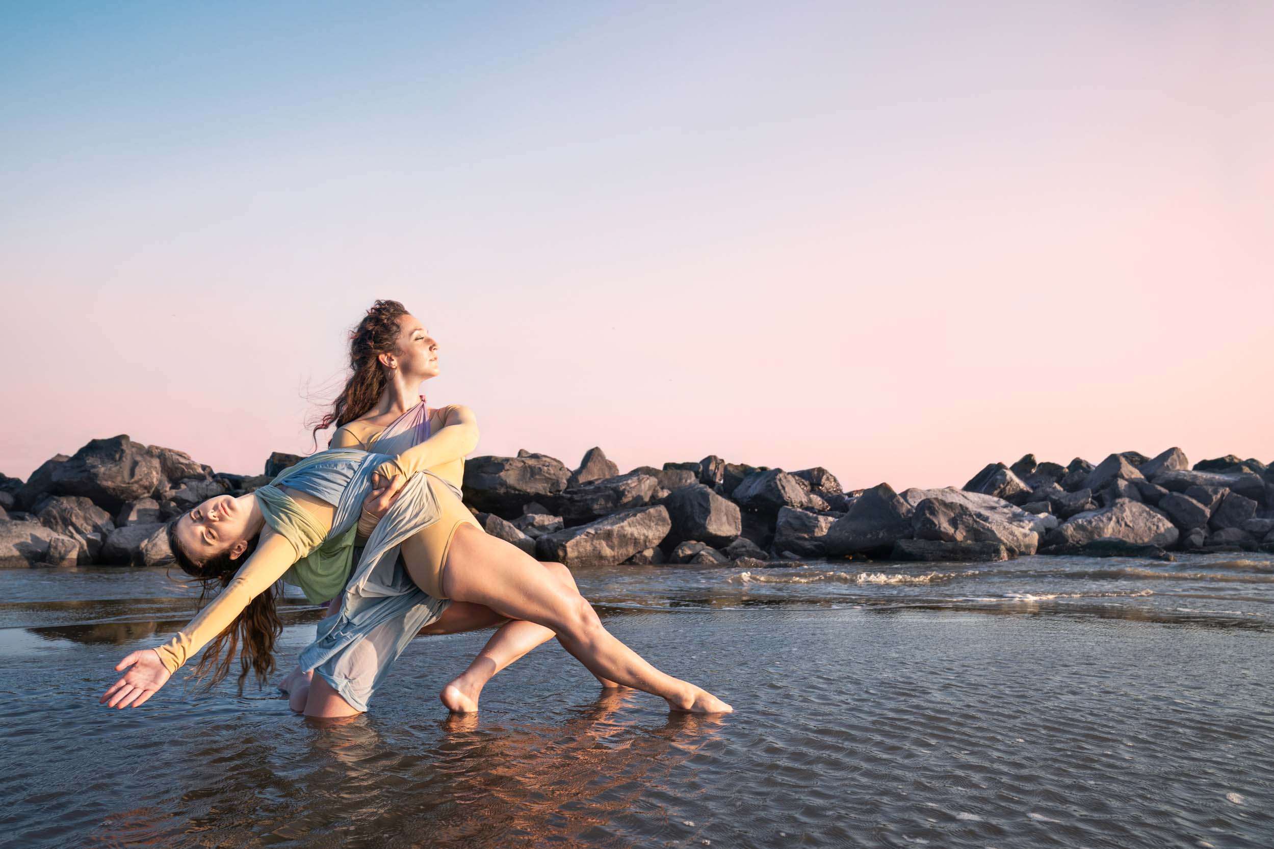 Female dancers holding each other on the beach at sunset along Louisiana Gulf Coast