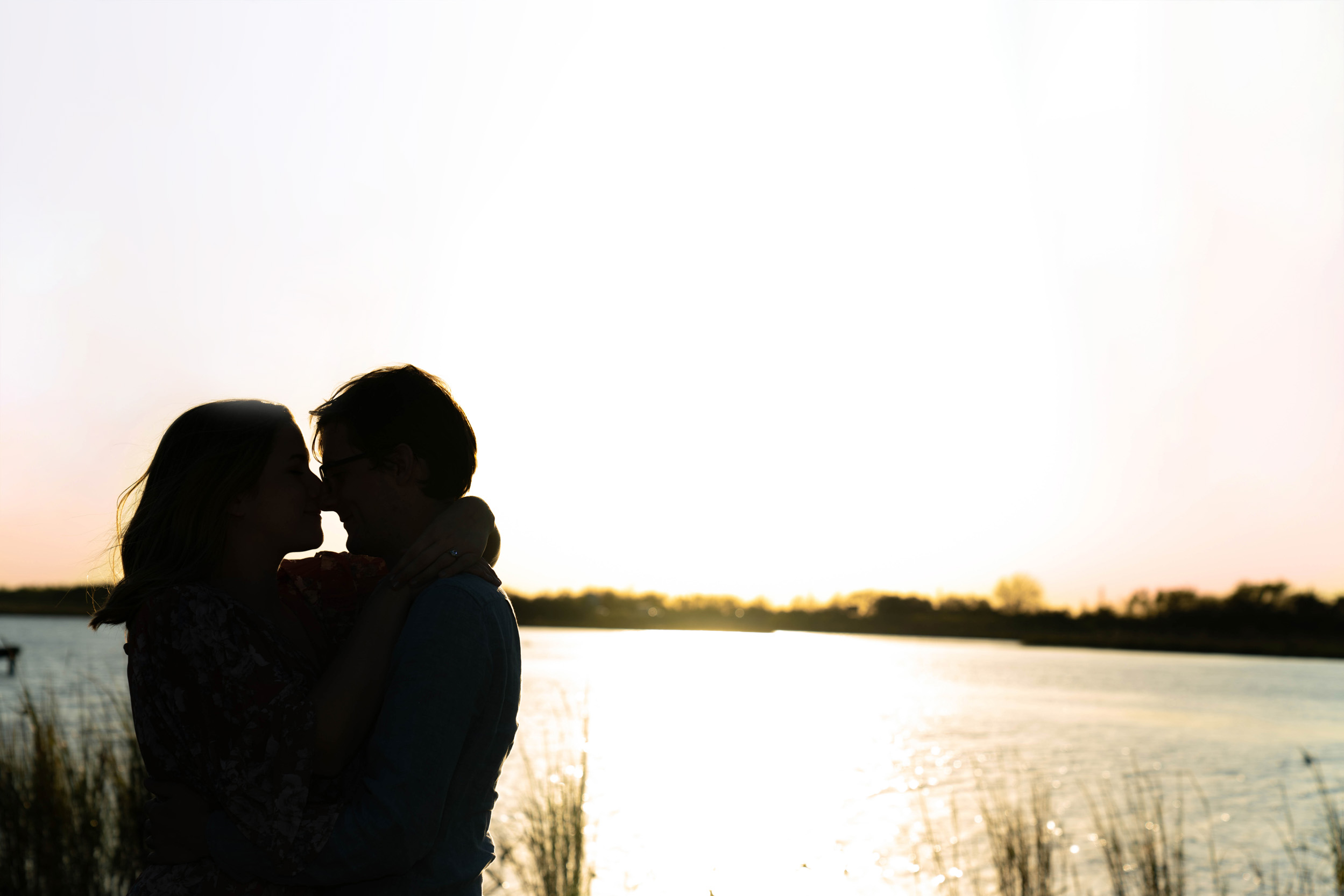 Engaged couple kissing along a bayou vista at sunset in Louisiana