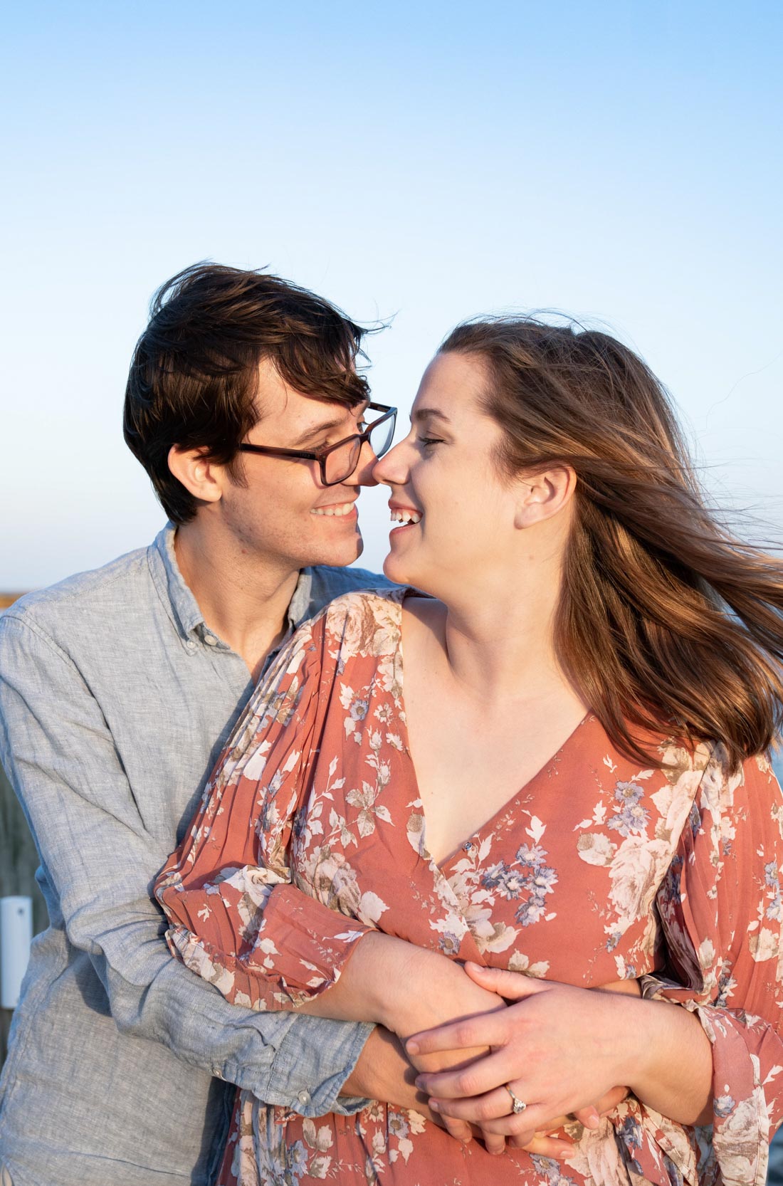Happy couple laughing together on a bayou dock at sunset in Louisiana after engagement proposal
