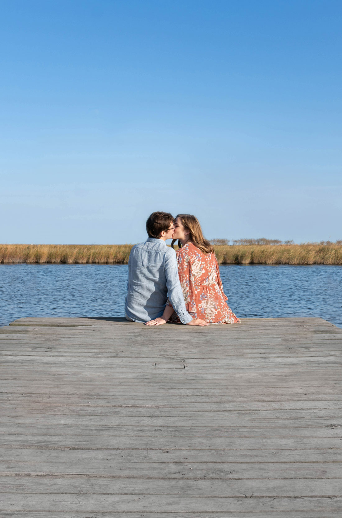 couple sitting on a bayou dock in Louisiana and kissing before proposal ceremony