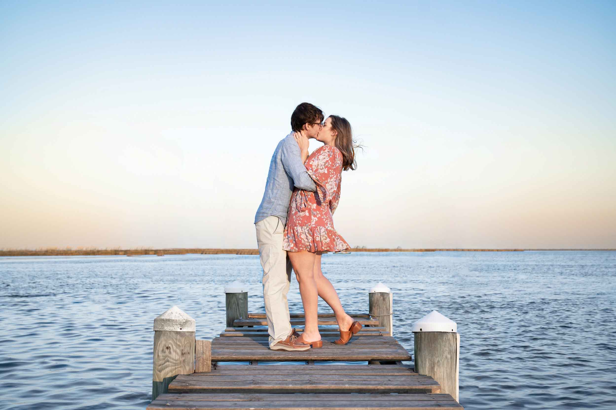 Couple kissing on a bayou dock at sunset in Louisiana after engagement proposal