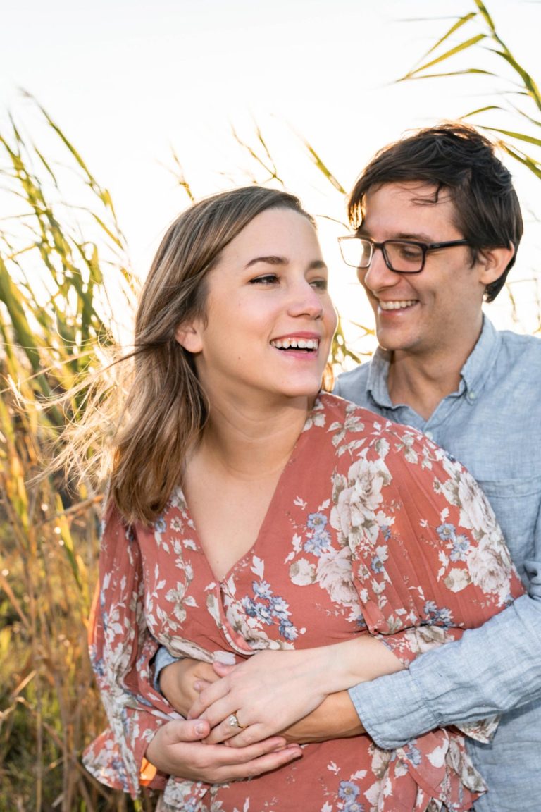 Happy couple laughing together in the grass along a bayou at sunset in Louisiana
