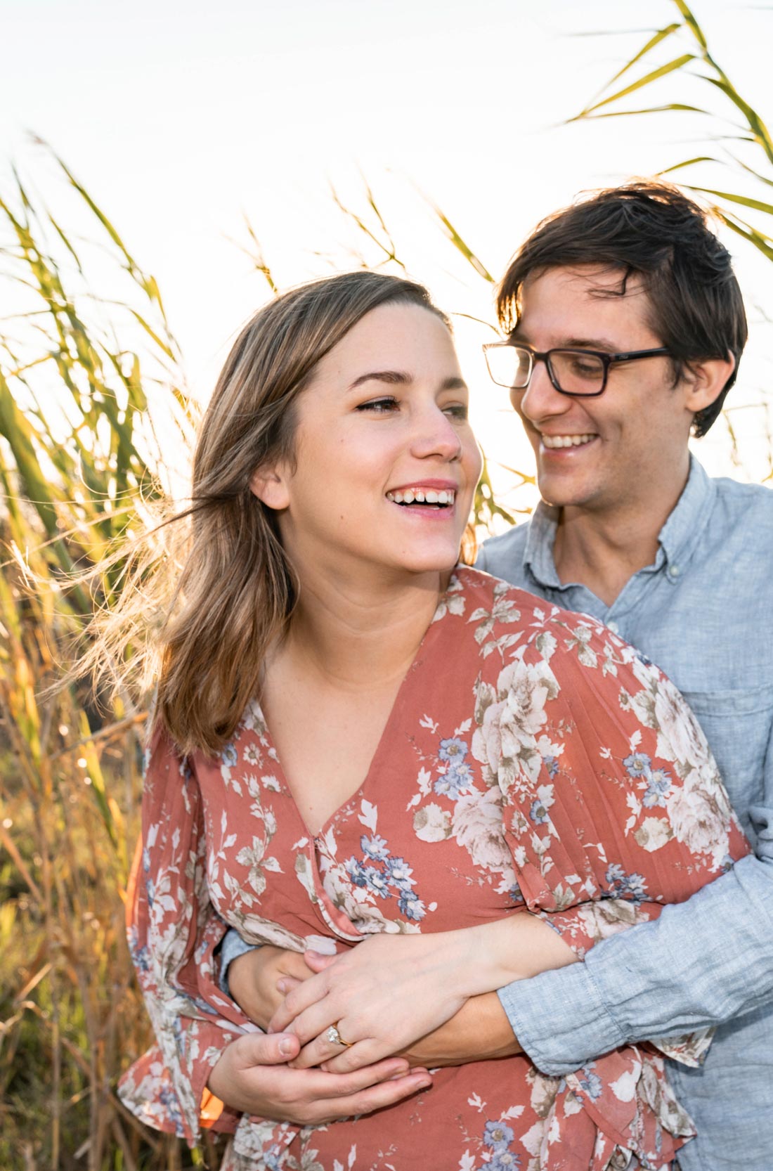 Happy couple laughing together in the grass along a bayou at sunset in Louisiana