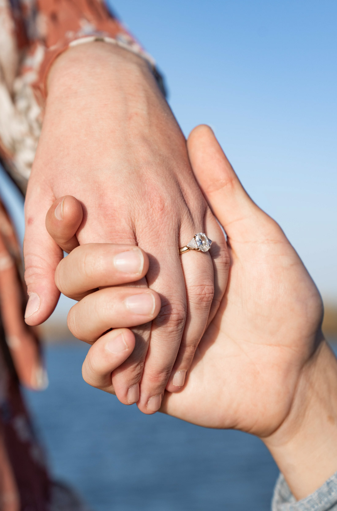Engagement proposal on a bayou vista of a couple holding hands with ring on finger