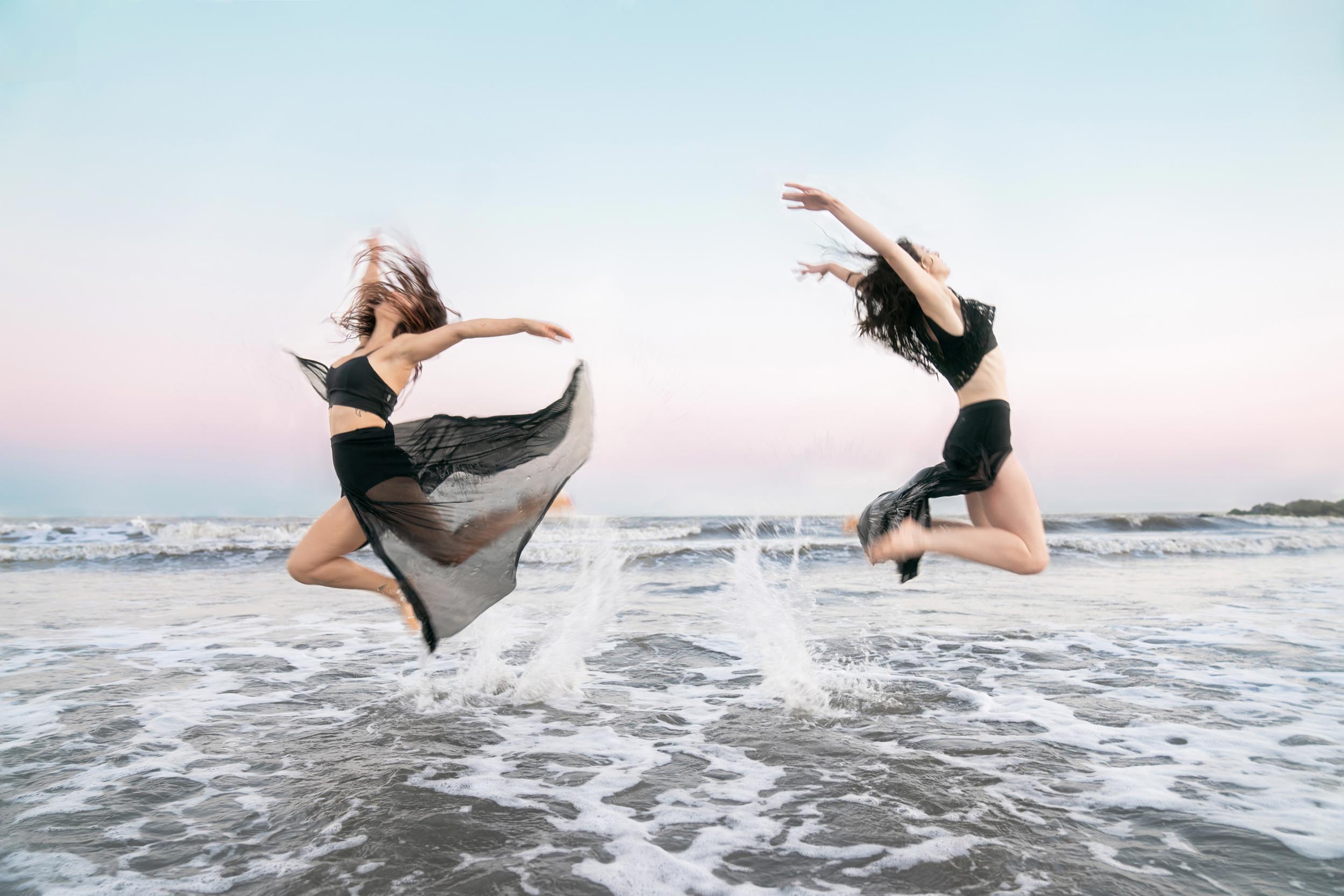 Dancers jumping and performing on the beach at sunset along Louisiana Gulf Coast