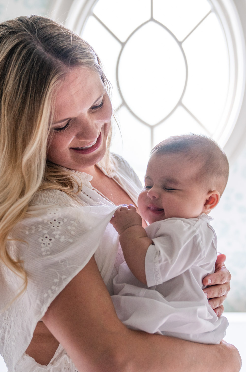 Mother holding baby smiling and laughing for newborn portrait