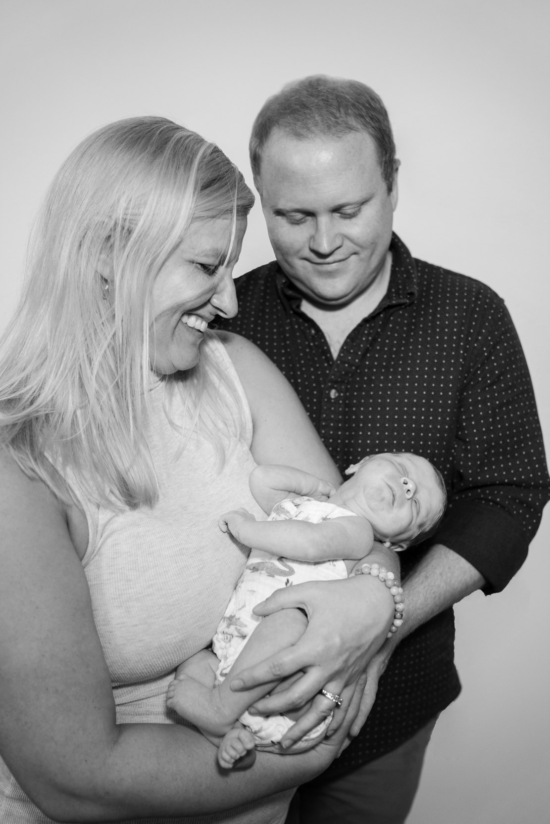 Mother and father smiling while they smile at newborn baby