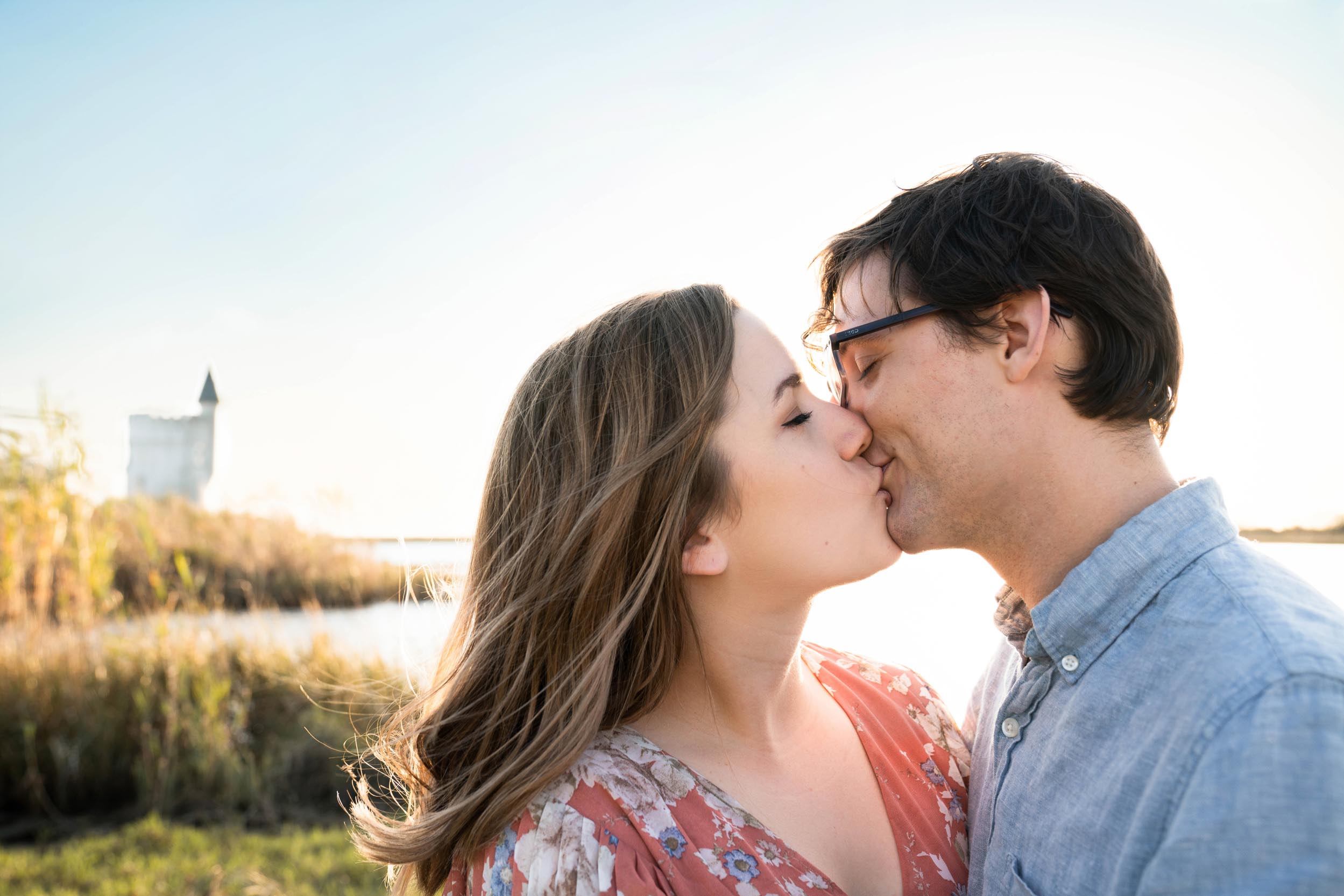 Happy couple kissing along Louisiana bayou after engagement proposal with castle in background