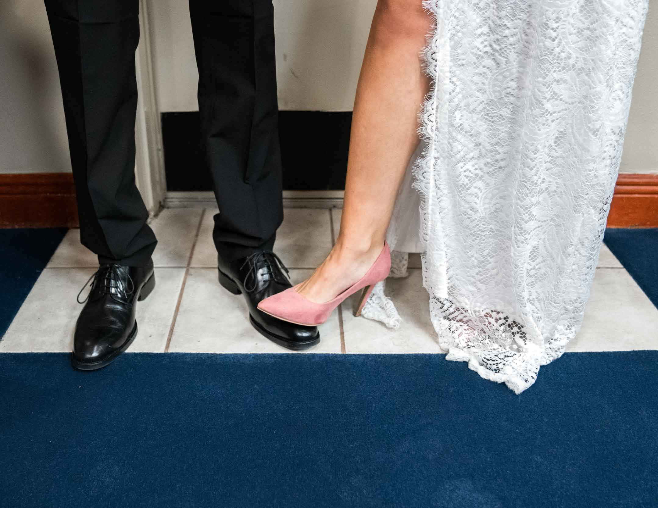 Bride and groom touching shoes on their wedding day
