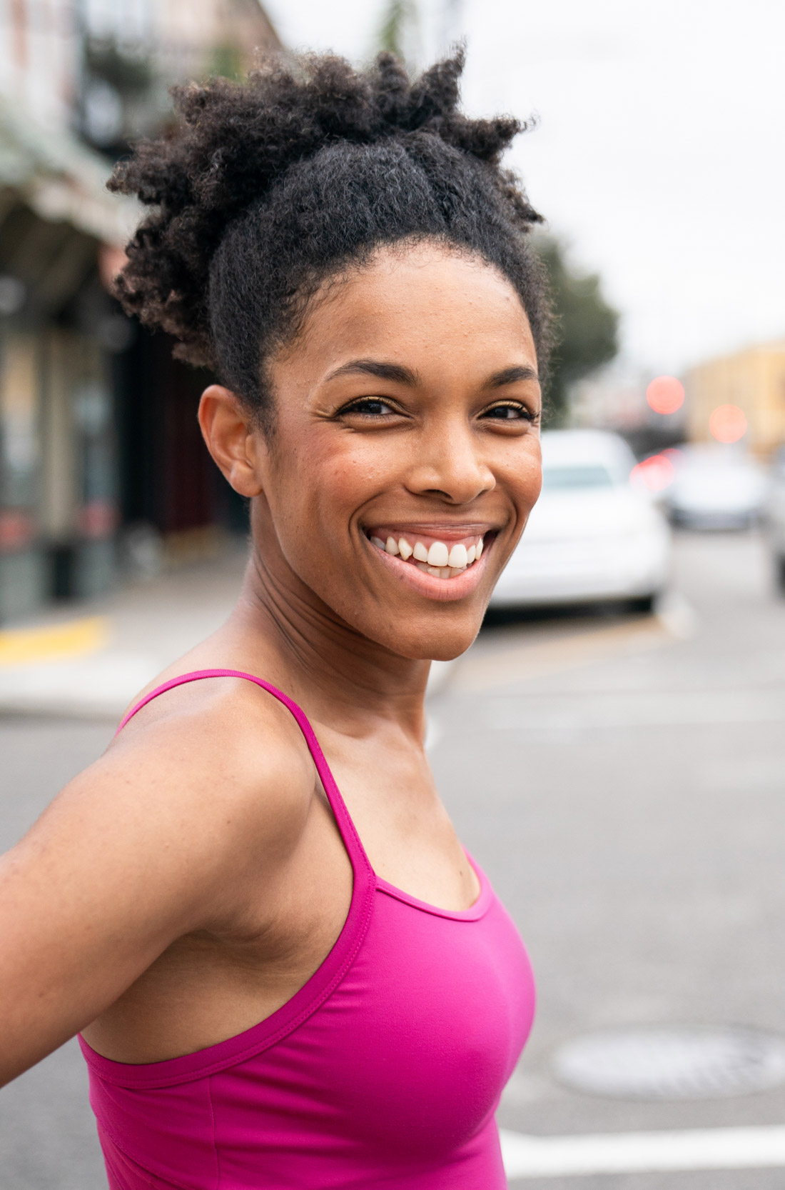 A female dancer wearing leotard smiling on a street in New Orleans
