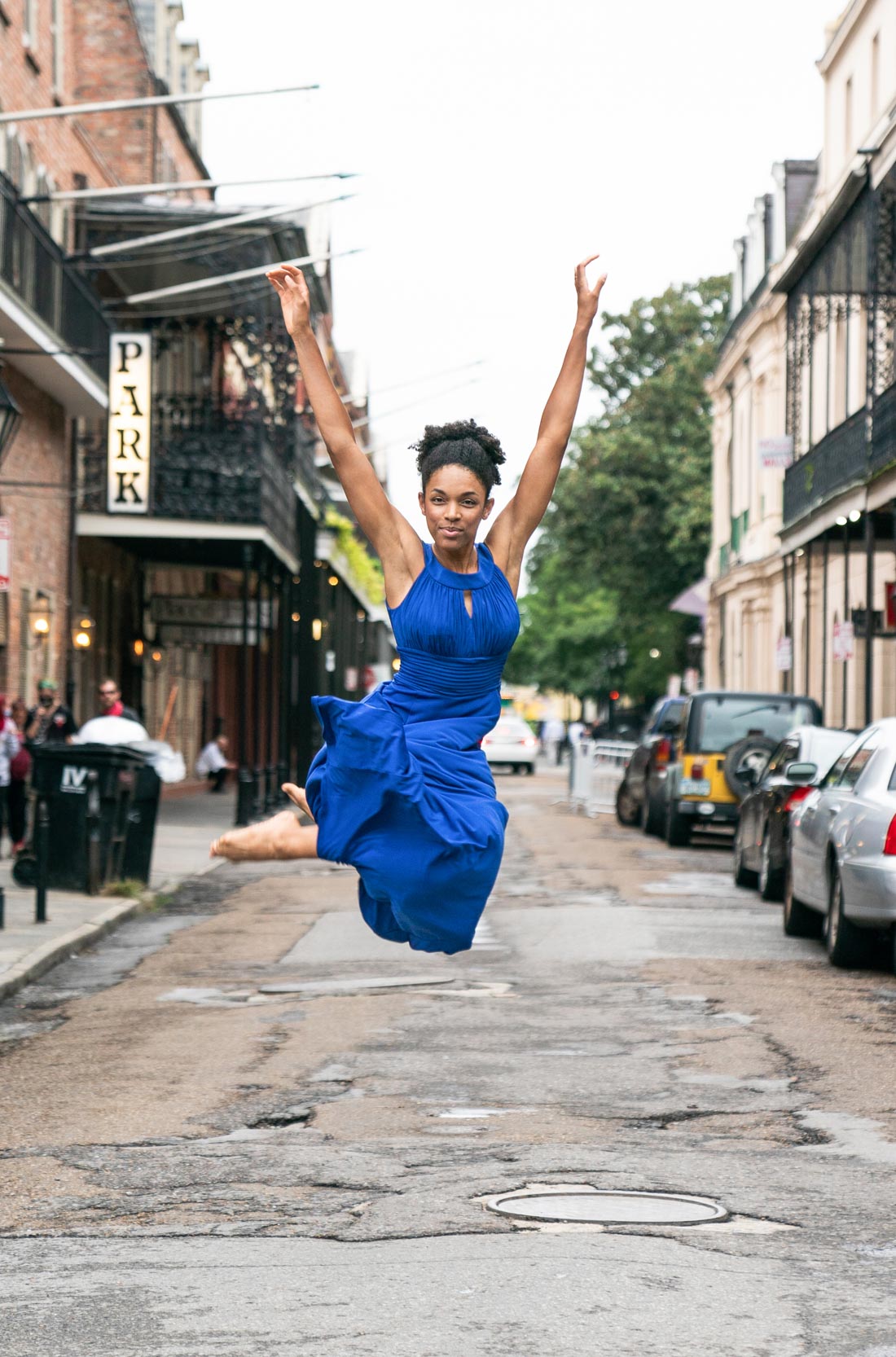 Female dancer in blue dress jumping in the air smiling in the New Orleans French Quarter