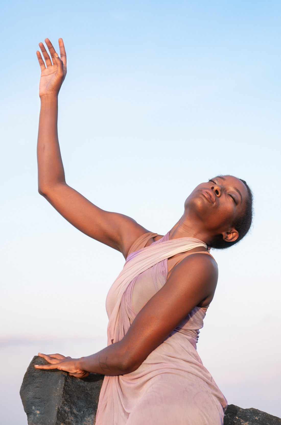 Female dancer meditating and reaching hand to the sky at sunset along Louisiana Gulf Coast beach