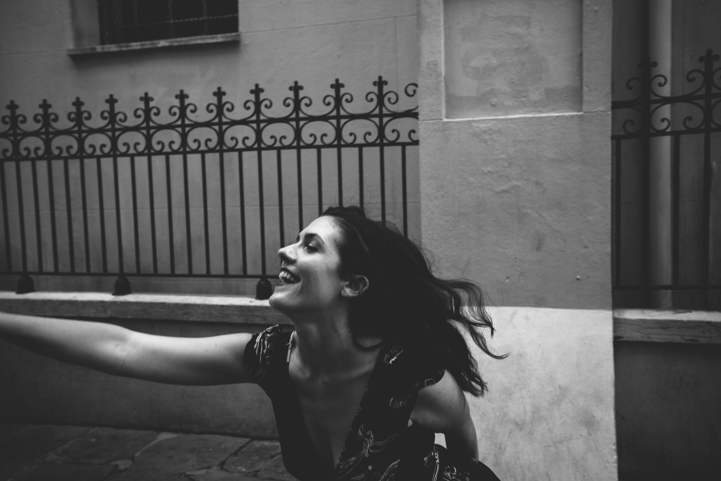 Woman dancing and smiling in an alleyway near a New Orleans French Quarter cathedral
