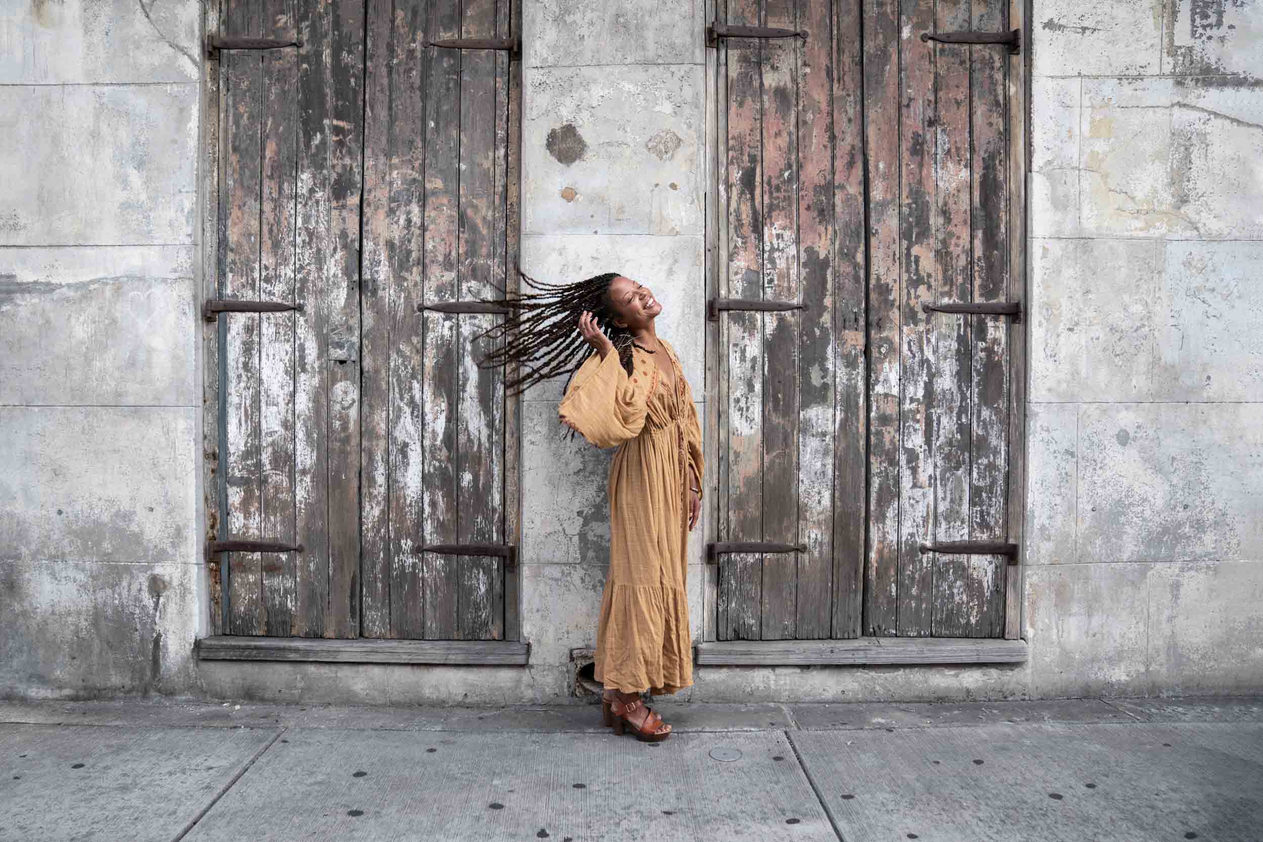Woman smiling and flipping hair in front of rustic house in the New Orleans French Quarter
