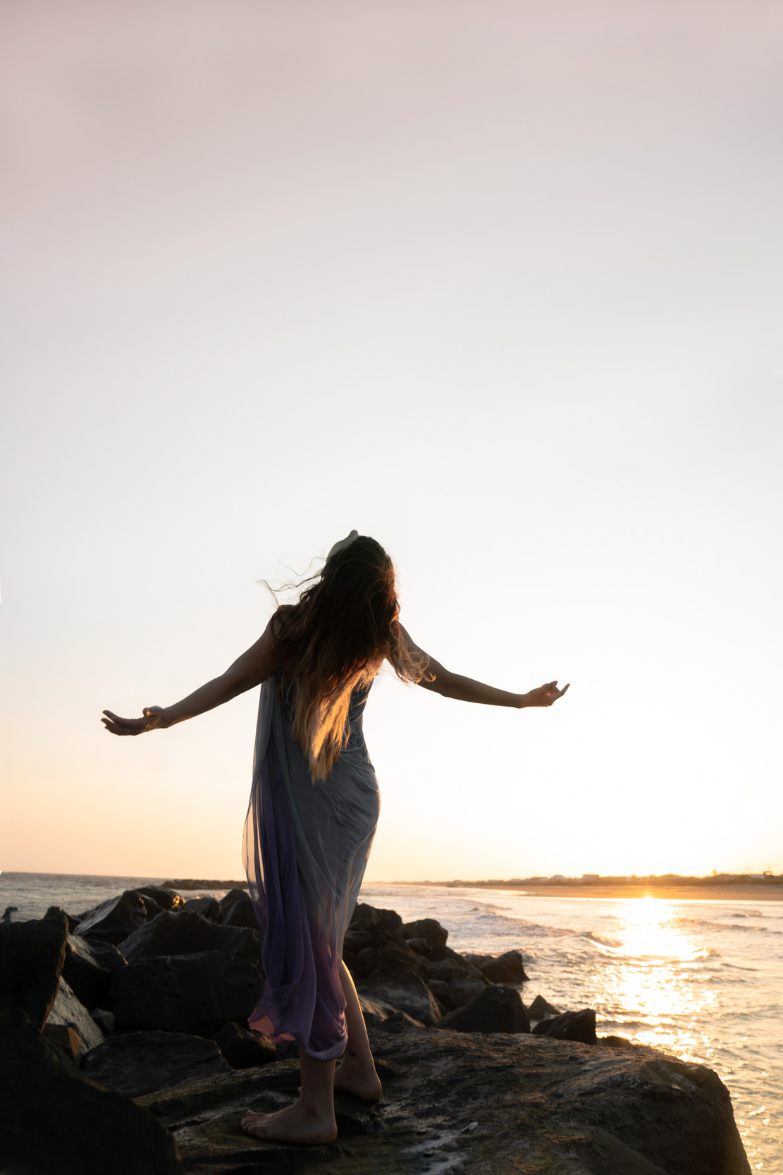 Dramatic pose by dancer with her arms out on the beach at sunset along Louisiana Gulf Coast