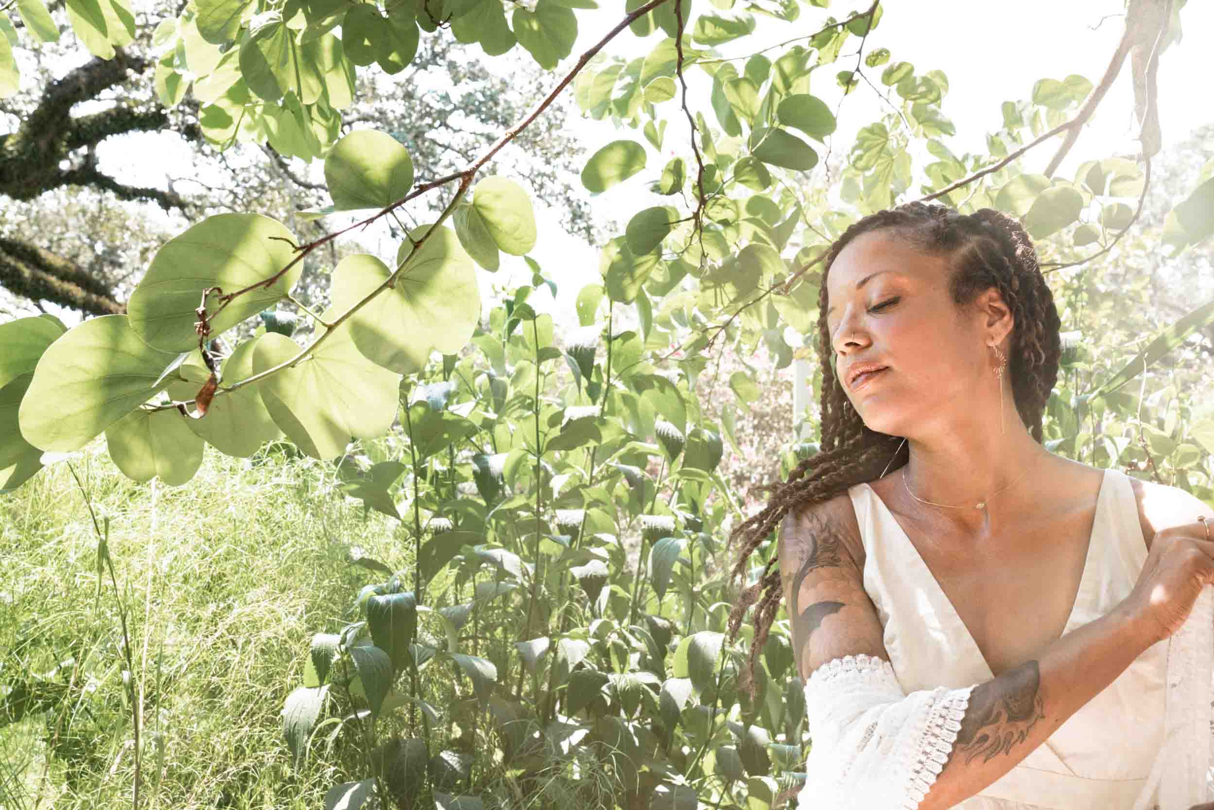 Woman meditating under trees on sunny day in New Orleans City Park Botanical Garden