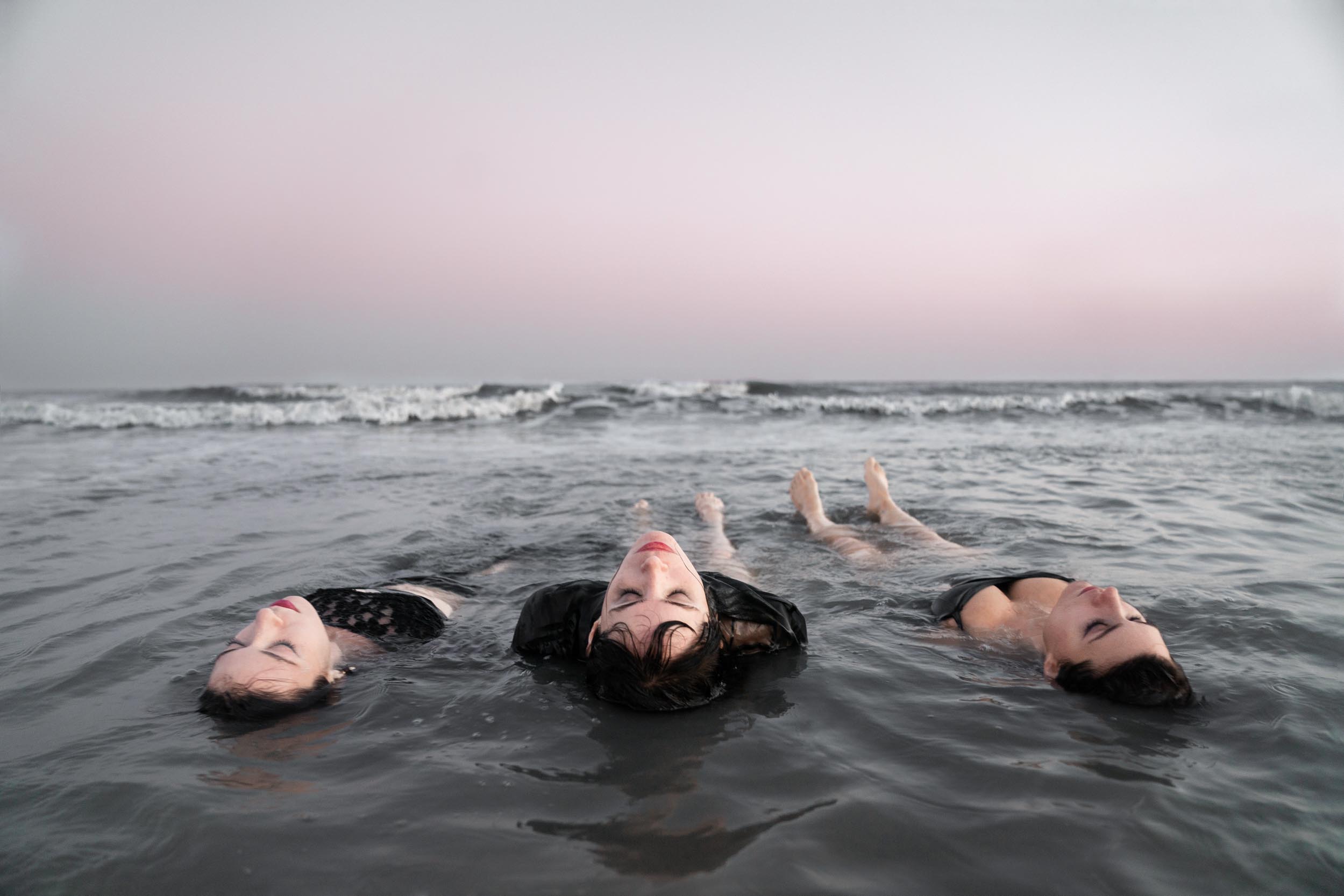 Female dancers laying in the ocean on a Louisiana Gulf Coast beach at sunset