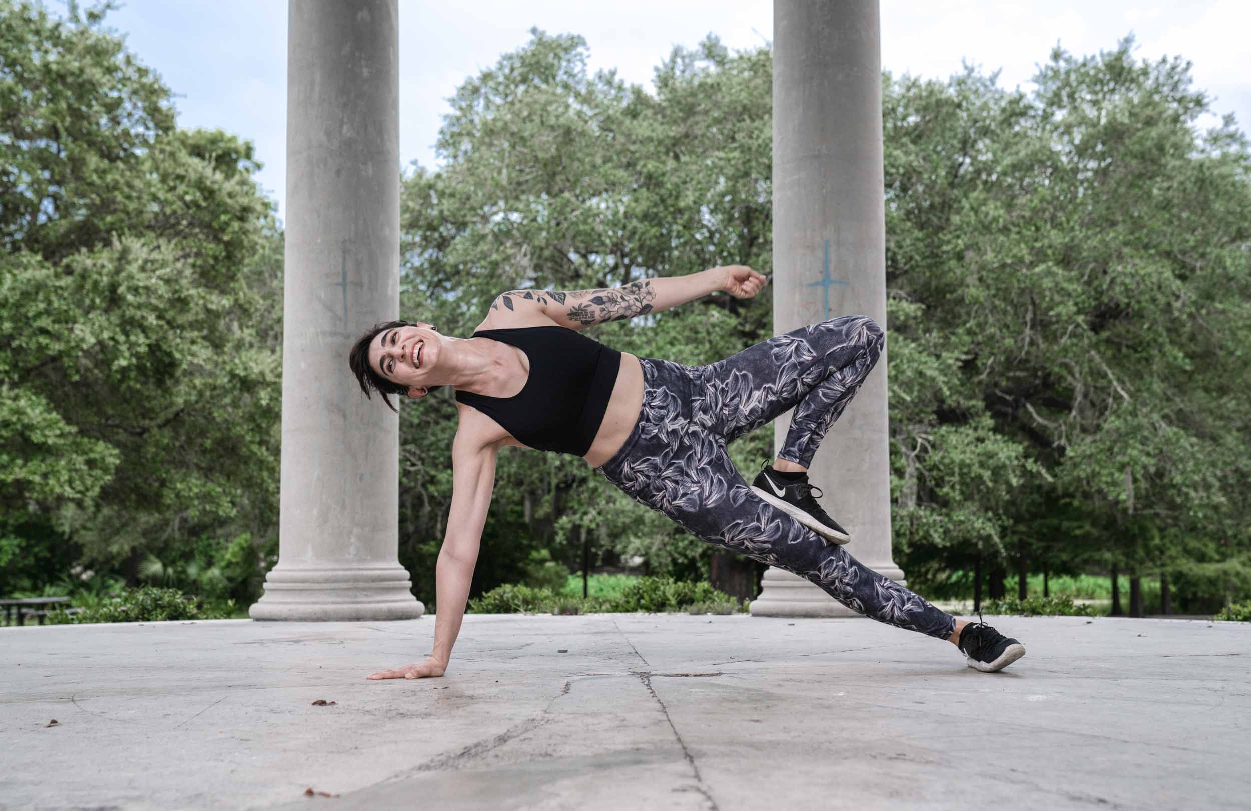 A yoga teacher smiling and laughing while posing on a monument in New Orleans City Park