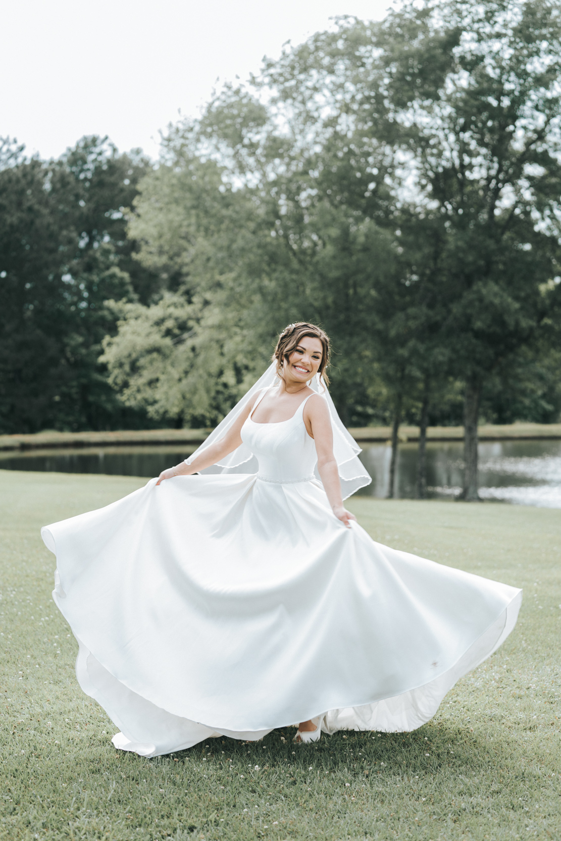 bride playing with dress in a field at White Magnola in Louisiana