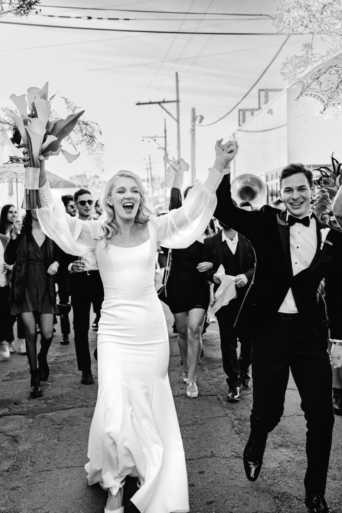 bride and groom parading with band in New Orleans on wedding day
