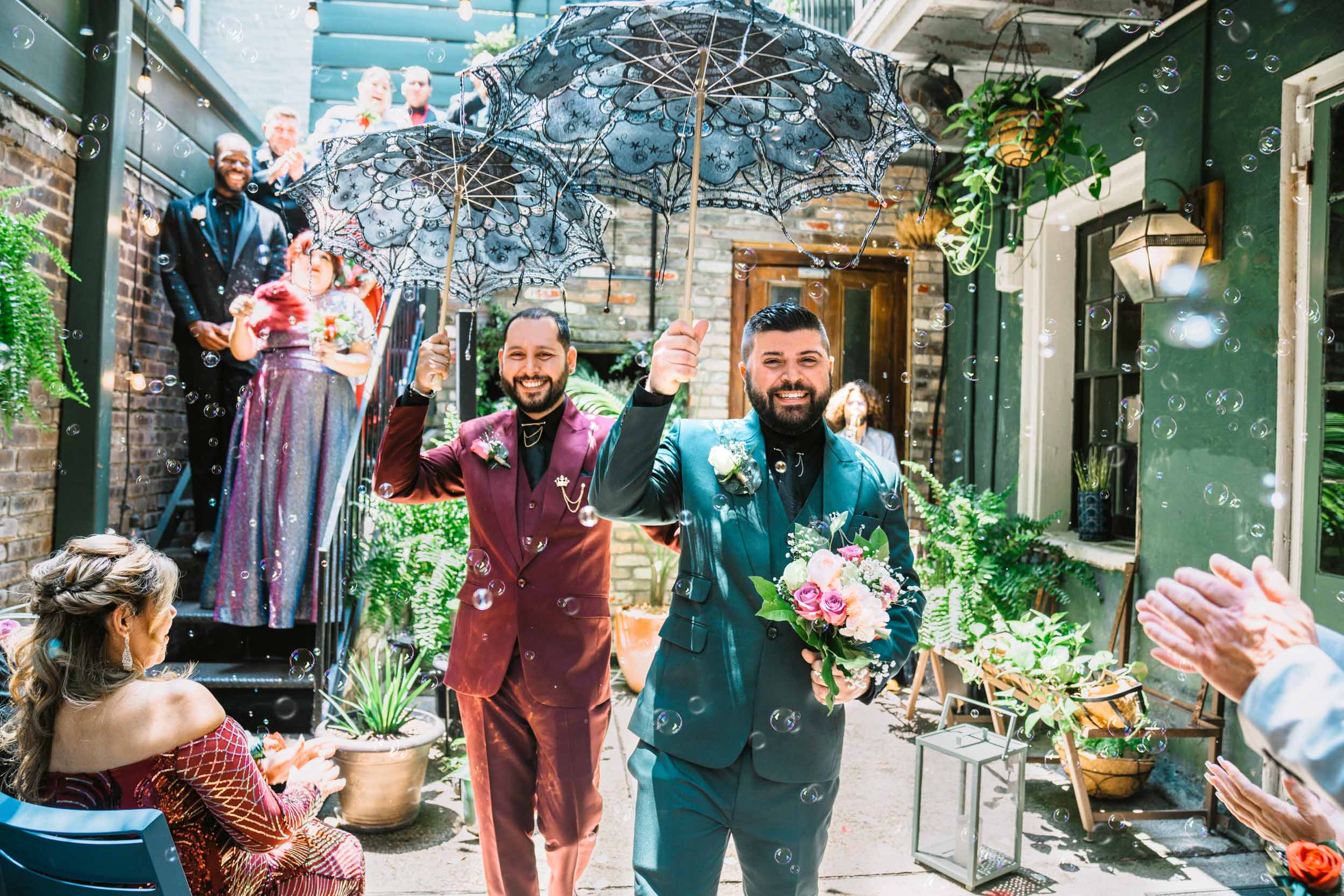 gay couple exiting their elopement ceremony with bubbles and umbrellas at Swoop Duggins House in New Orleans