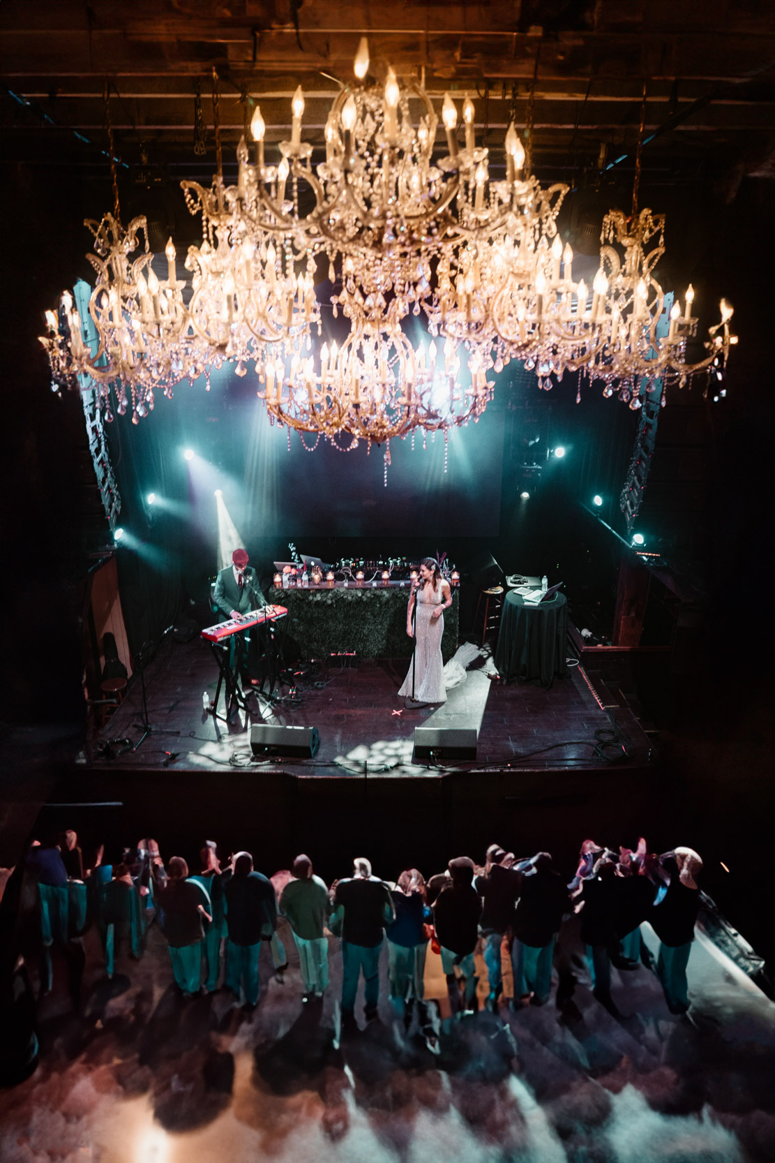 bride and groom performing a song on stage with chandelier at The Republic venue in New Orleans