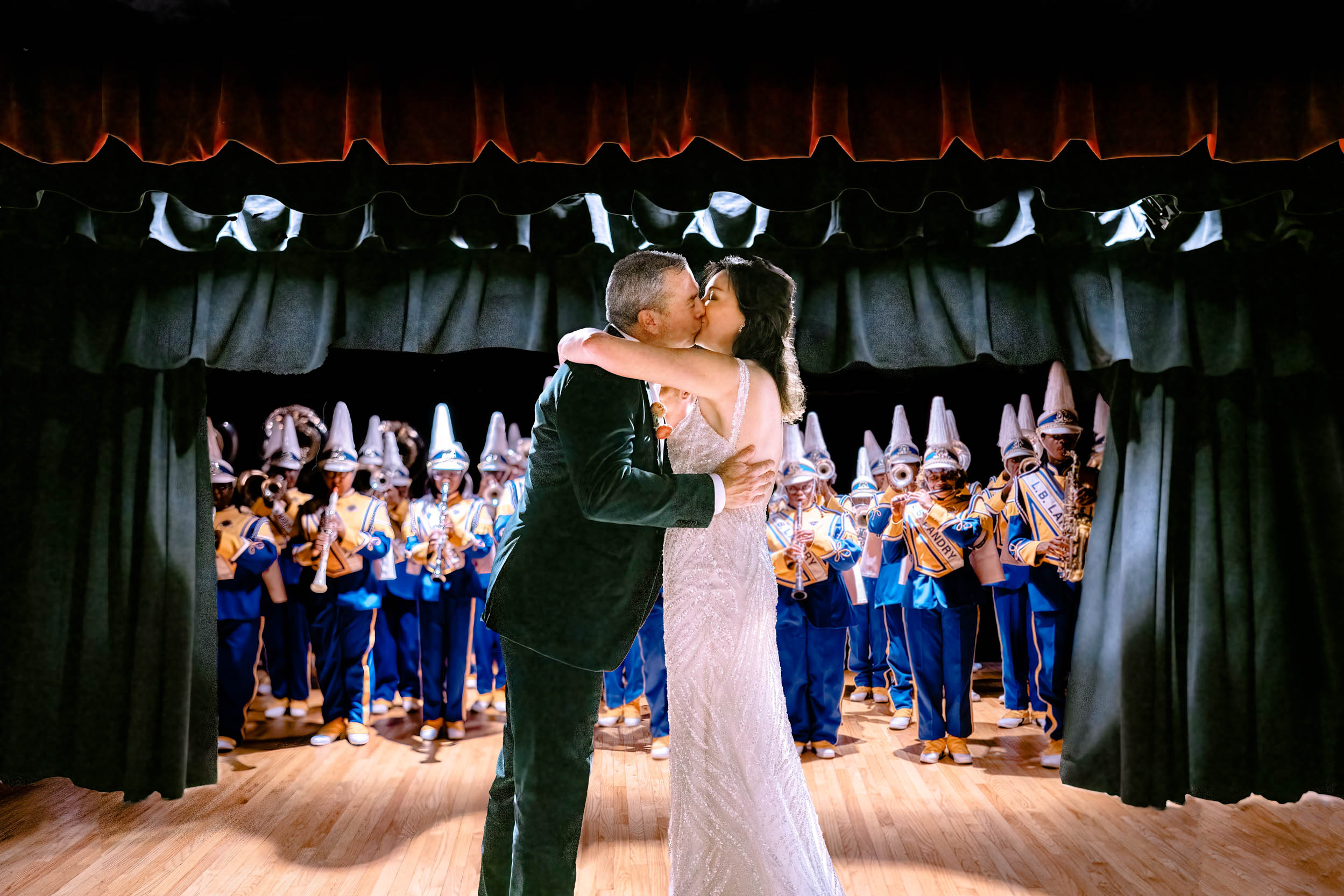 Bride and groom kissing with marching band at Gallier Hall in New Orleans