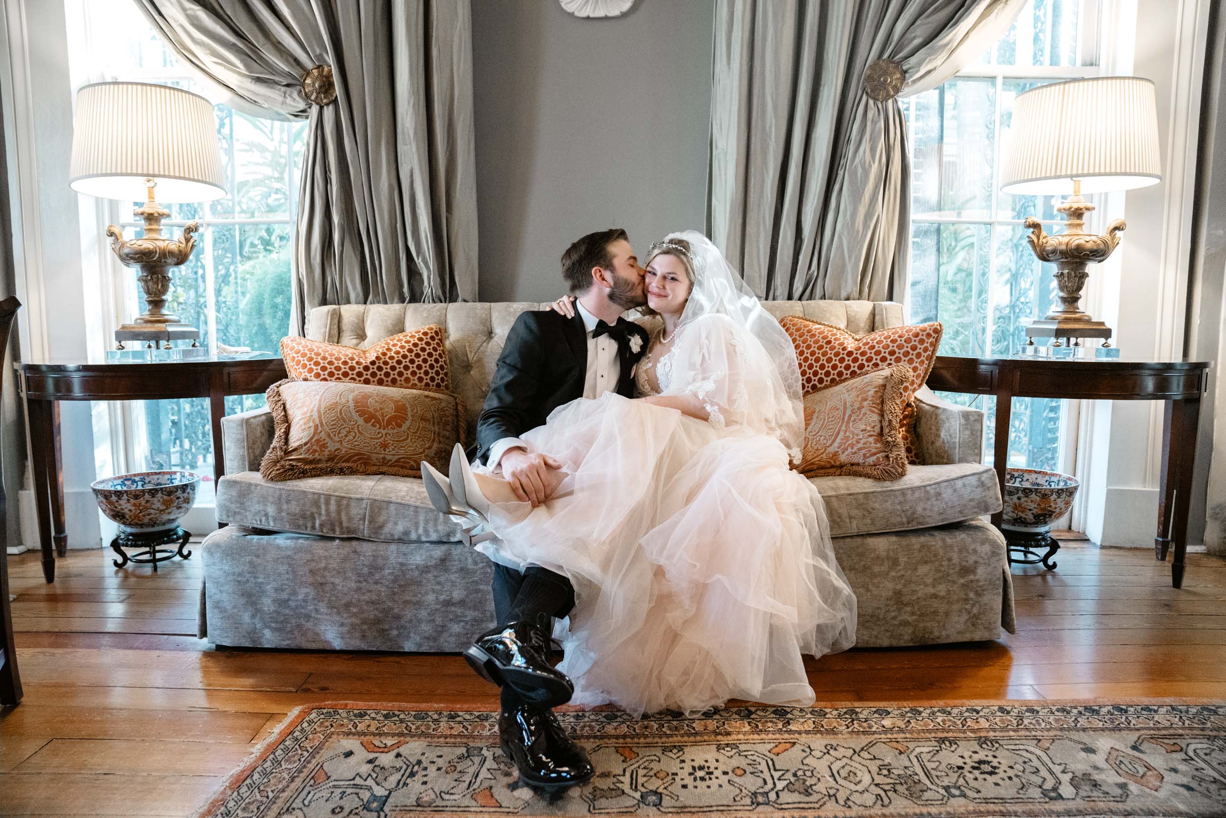 bride and groom smiling on a couch at the Tourelle House in New Orleans