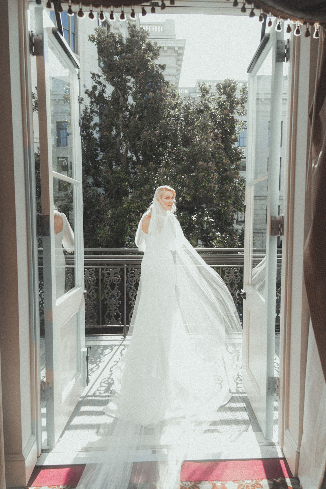 Bride on balcony in the French Quarter turning back with veil
