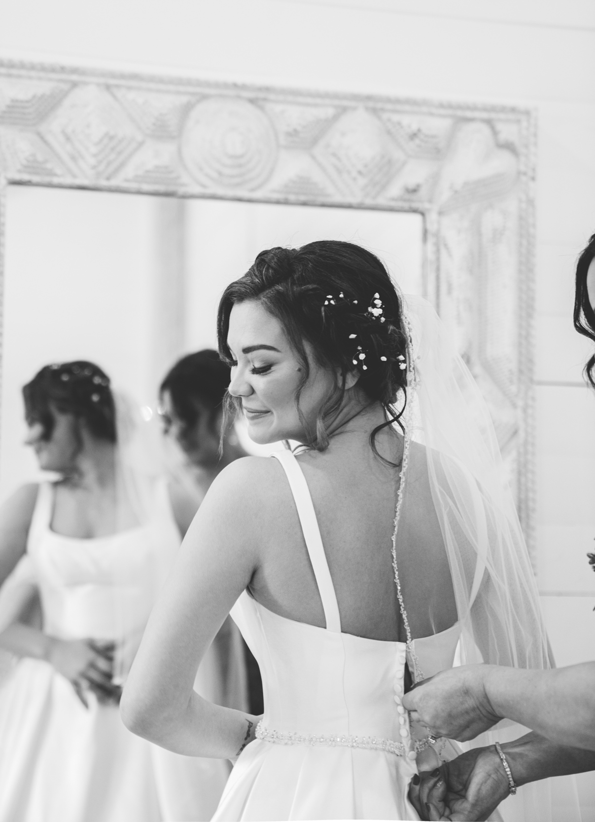 bride getting buttoned up in mirror by her mother at White Magnolia in Louisiana
