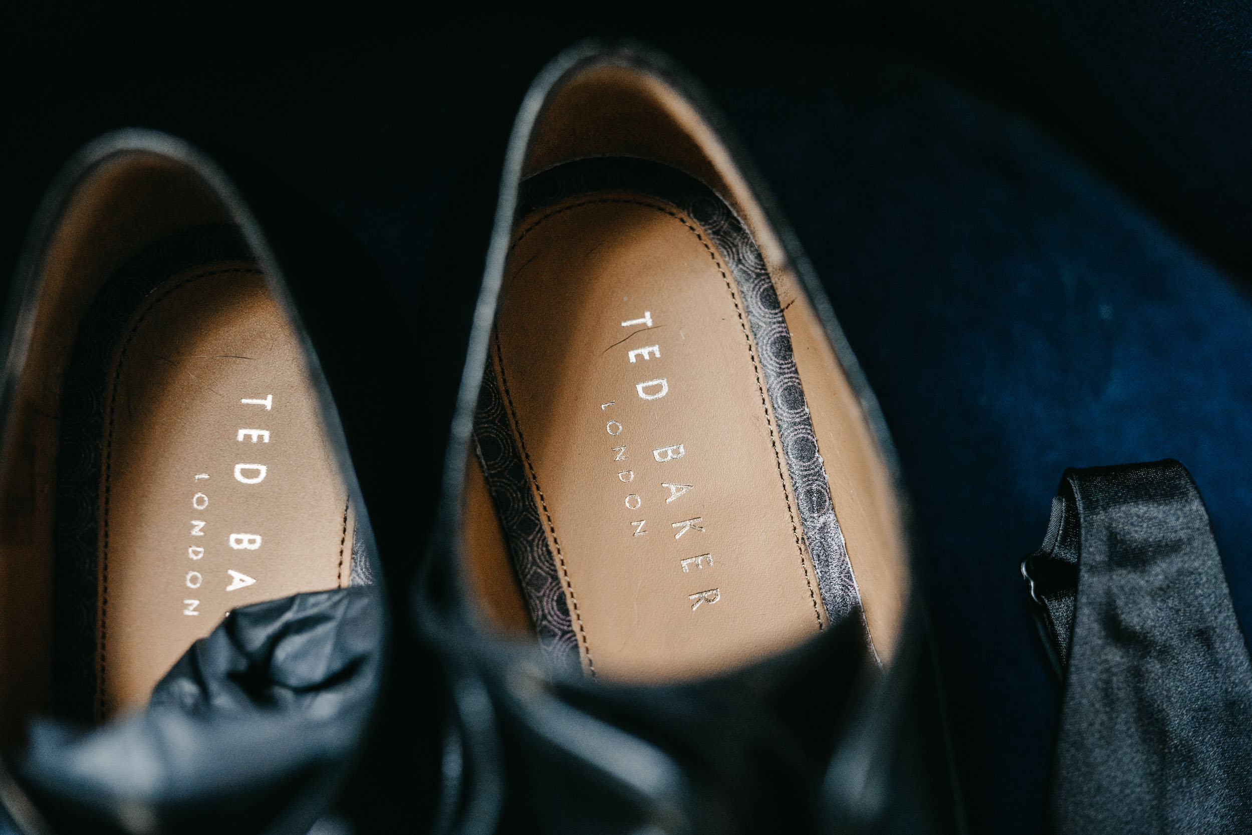 Ted Baker groom's shoes made of black leather on top of blue velvet