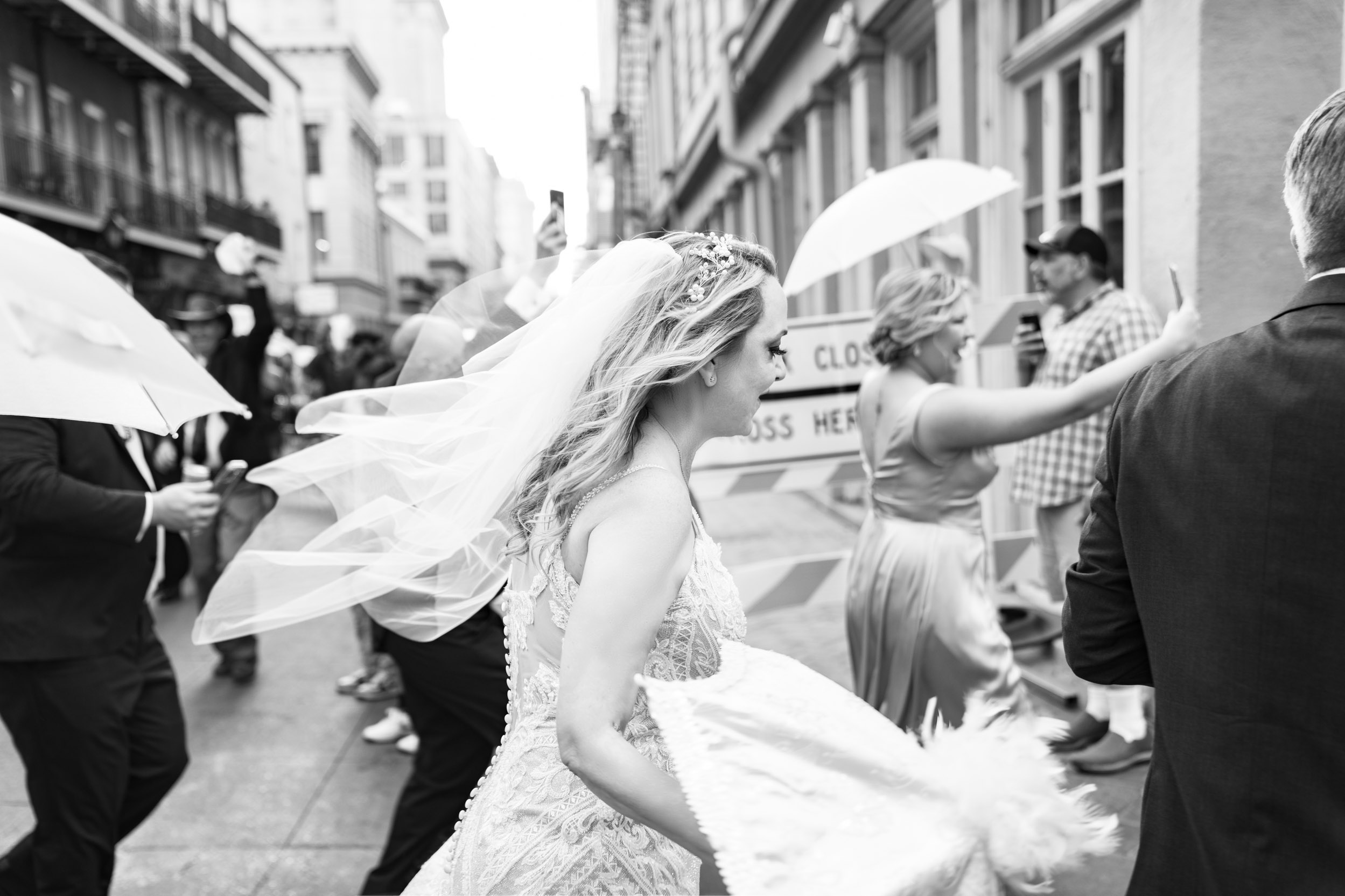 bride's veil flying and celebrating with wedding parade in street of the French Quarter in New Orleans