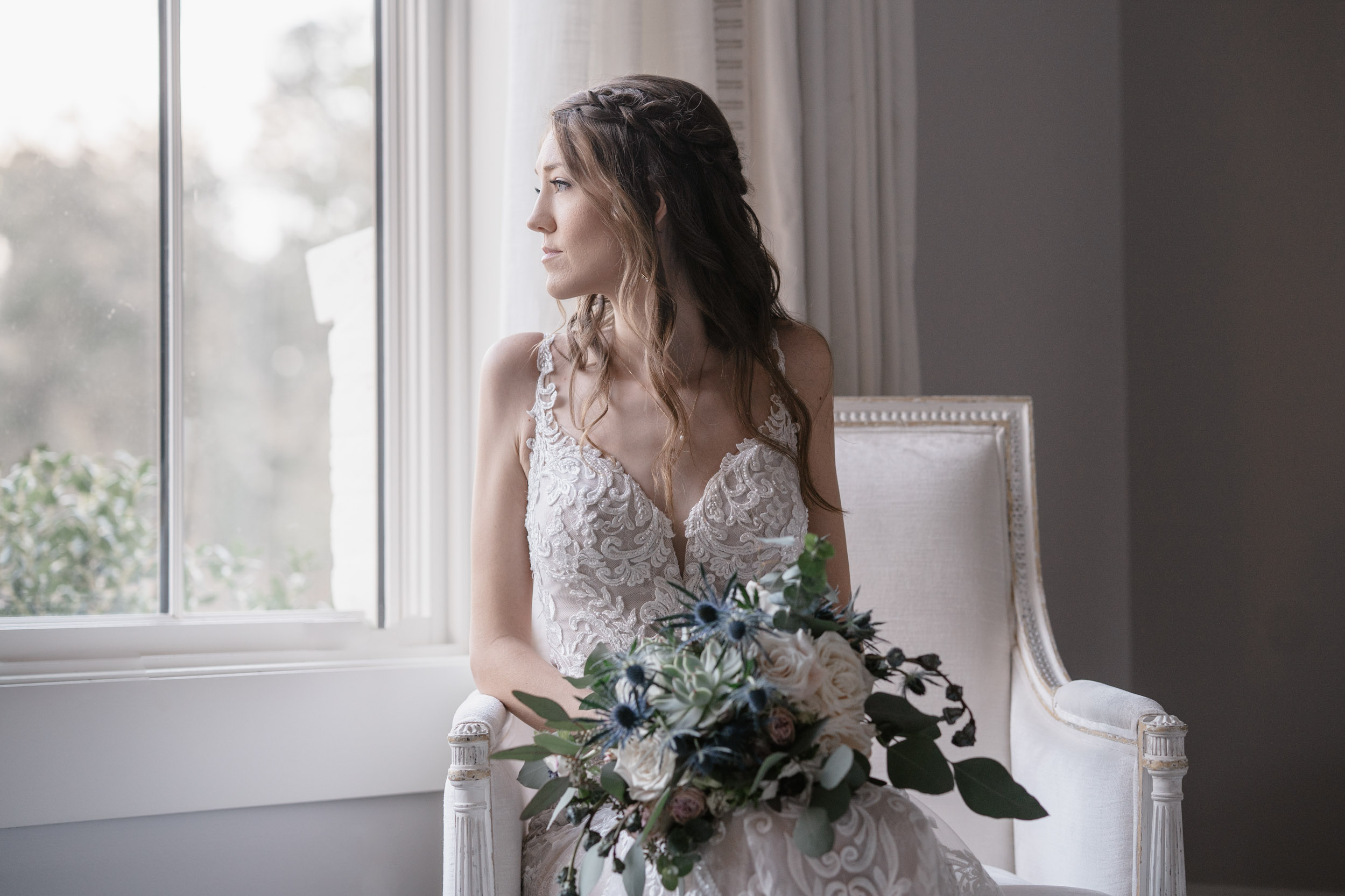 bride looking out window with flowers on her wedding day