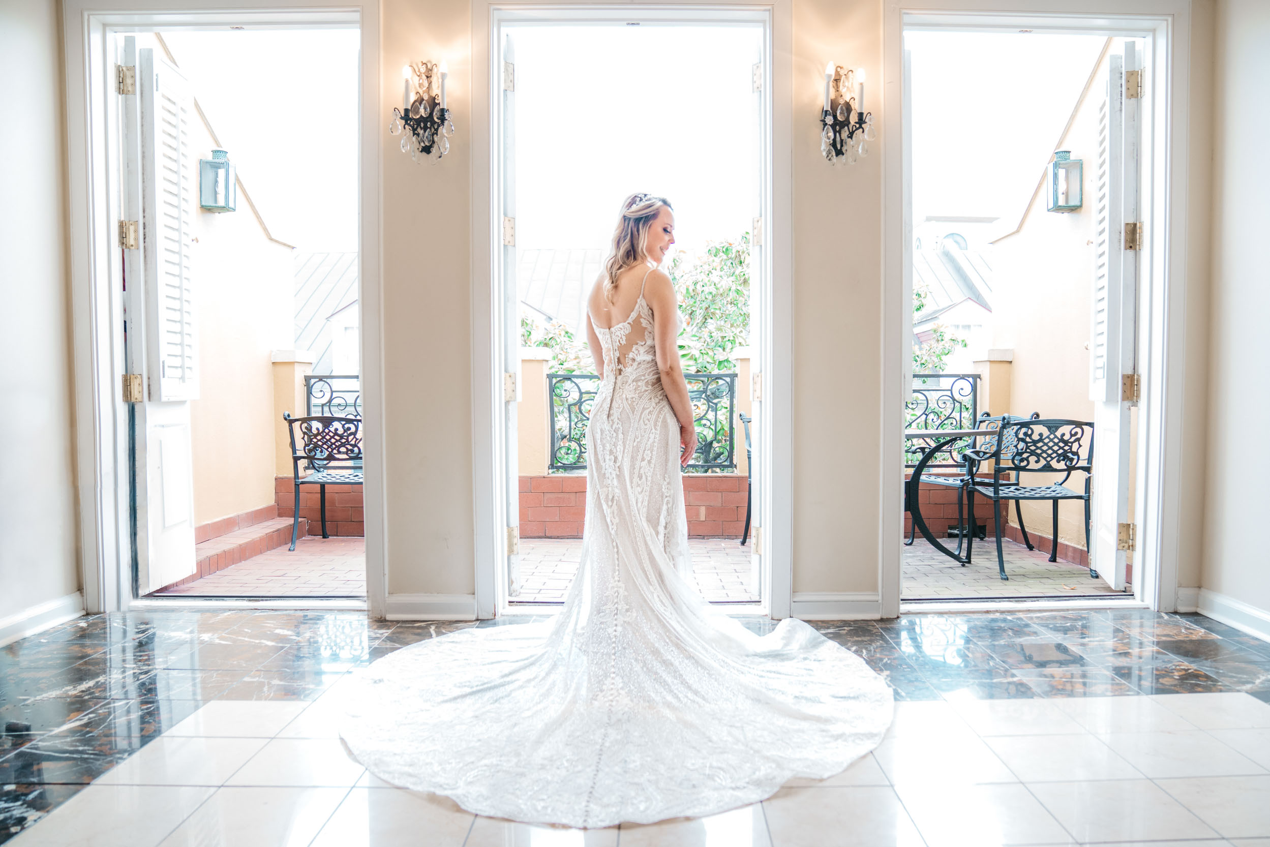 bride posing with doors and windows open in her suite in the French Quarter in New Orleans
