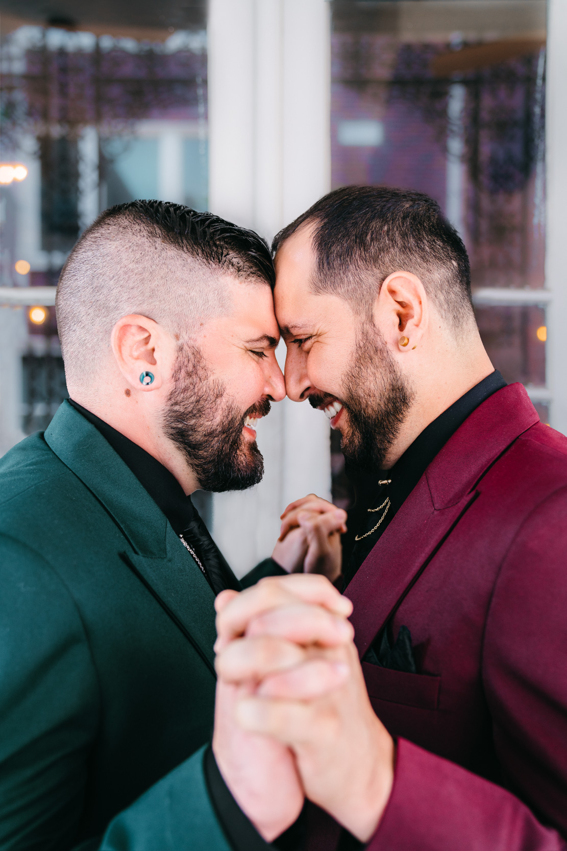 gay couple touching foreheads and holding hands during elopement ceremony