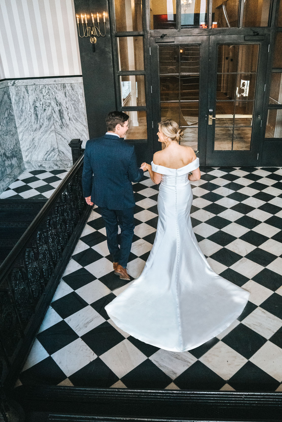 bride and groom walking on checkered floor at the Maison De La Luz Hotel in New Orleans
