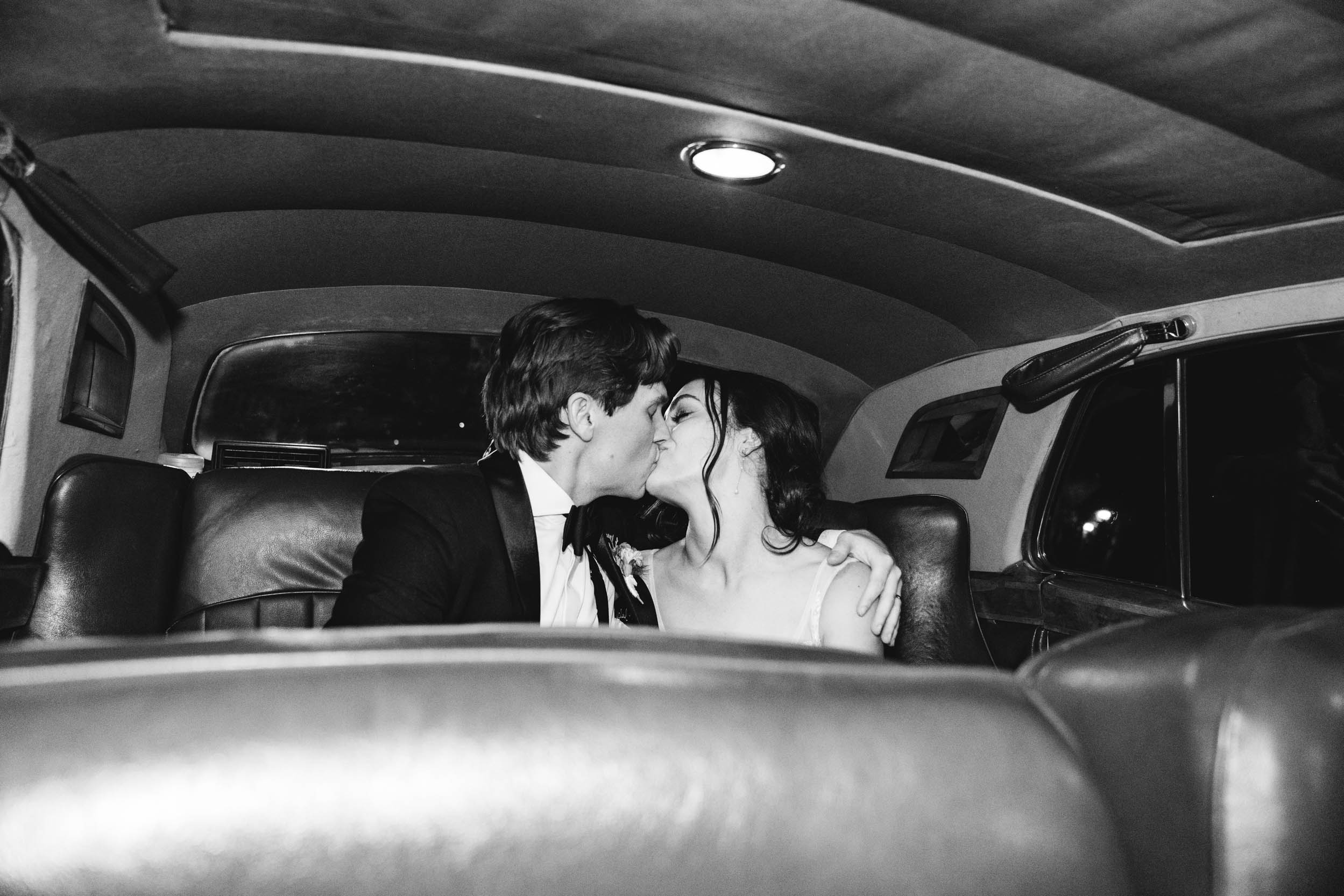 bride and groom kissing in the backseat of antique car on wedding day at Maison Lafitte in Covington, Louisiana