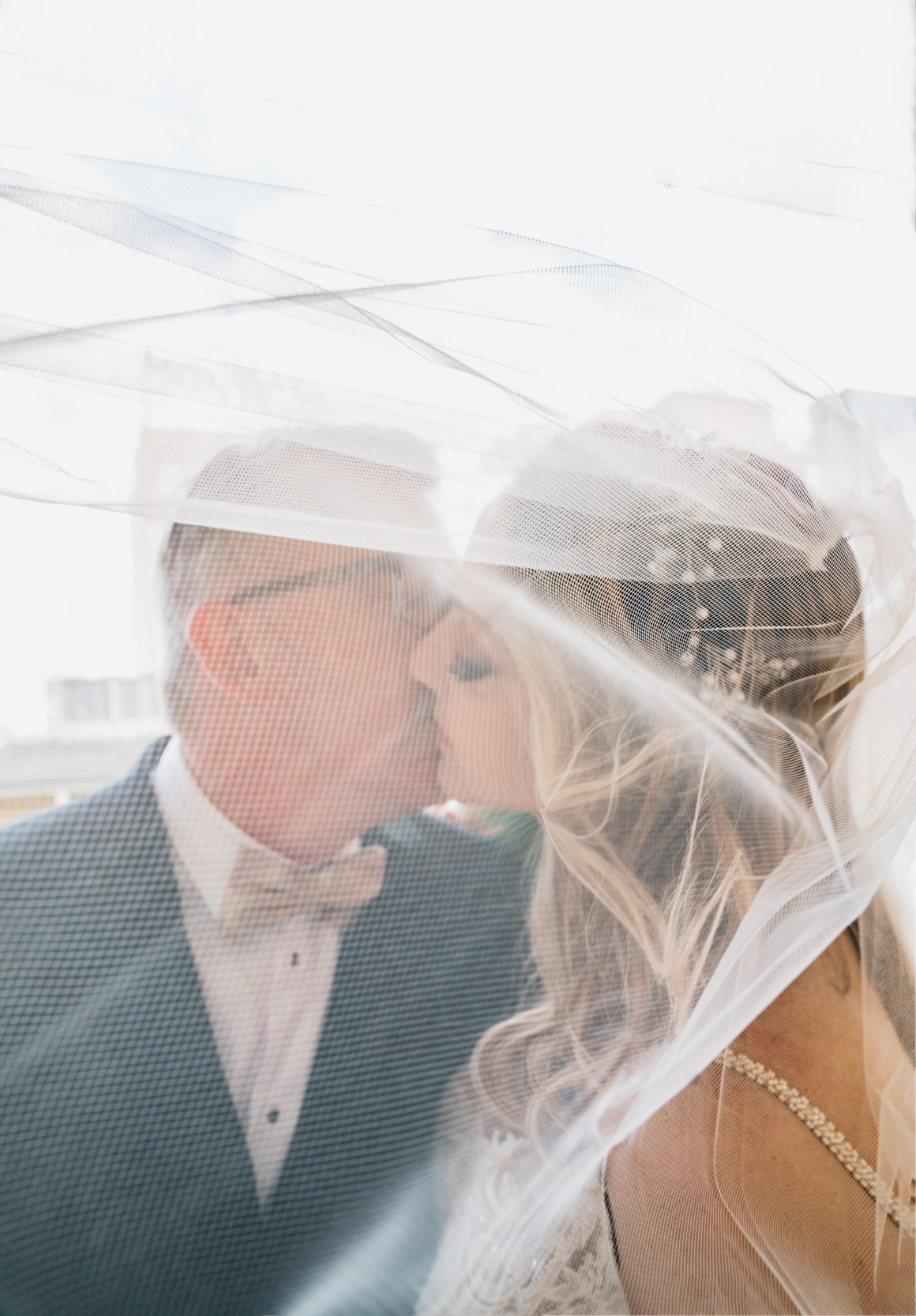 groom kissing bride while veil blows in The French Quarter