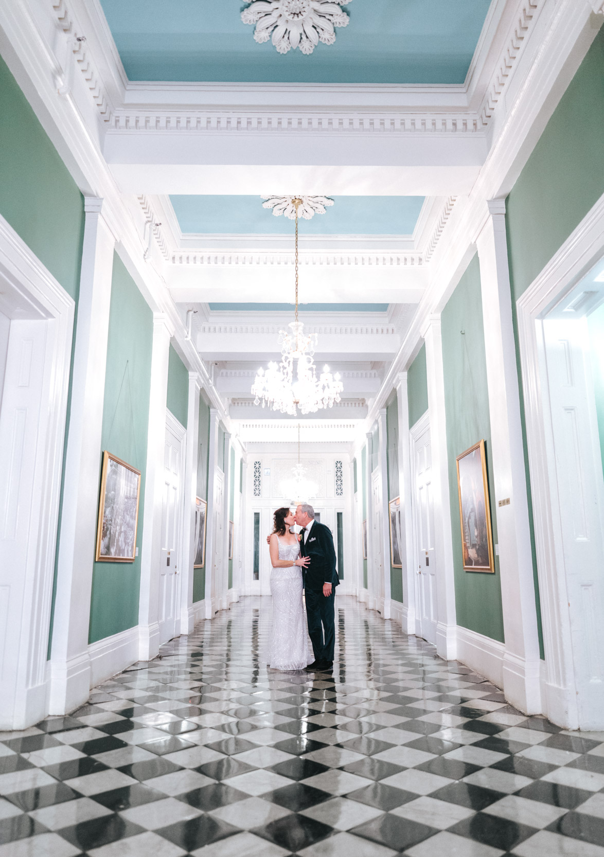 Bride and groom kissing on top of checkered floor at Gallier Hall in New Orleans