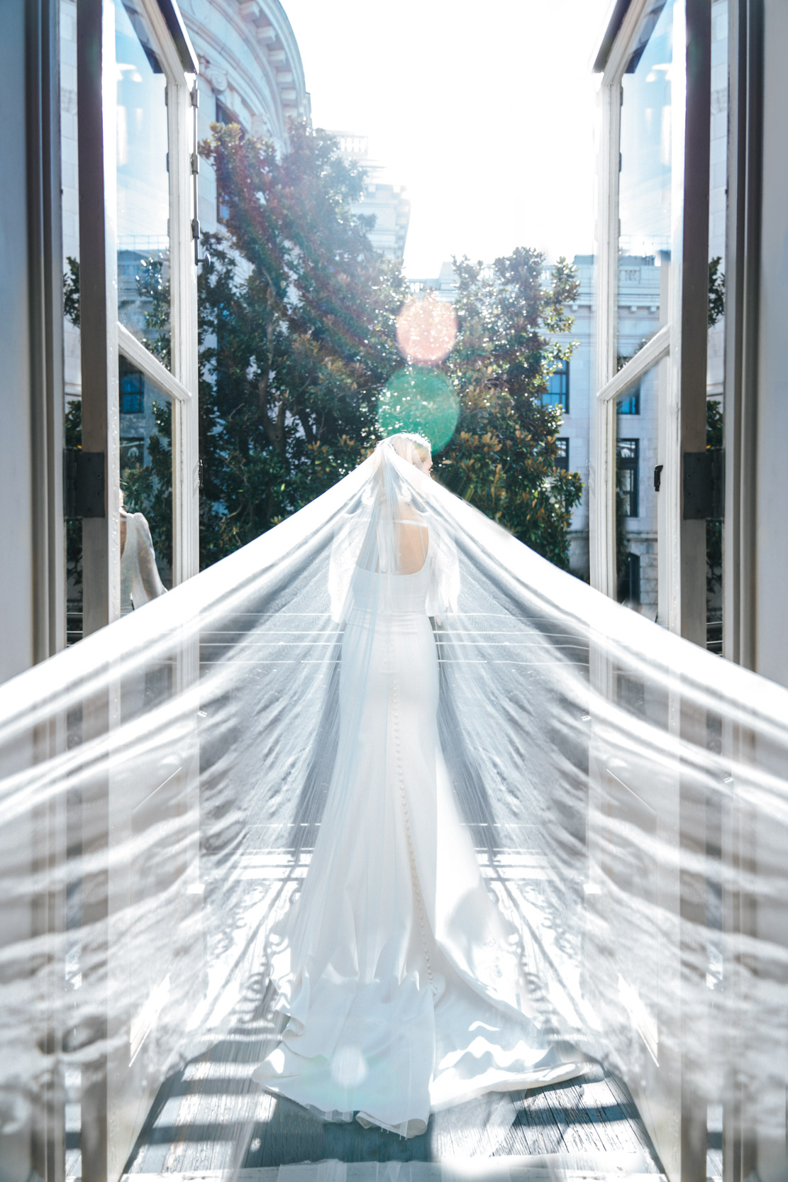 Bride standing on balcony in the French Quarter while veil blows