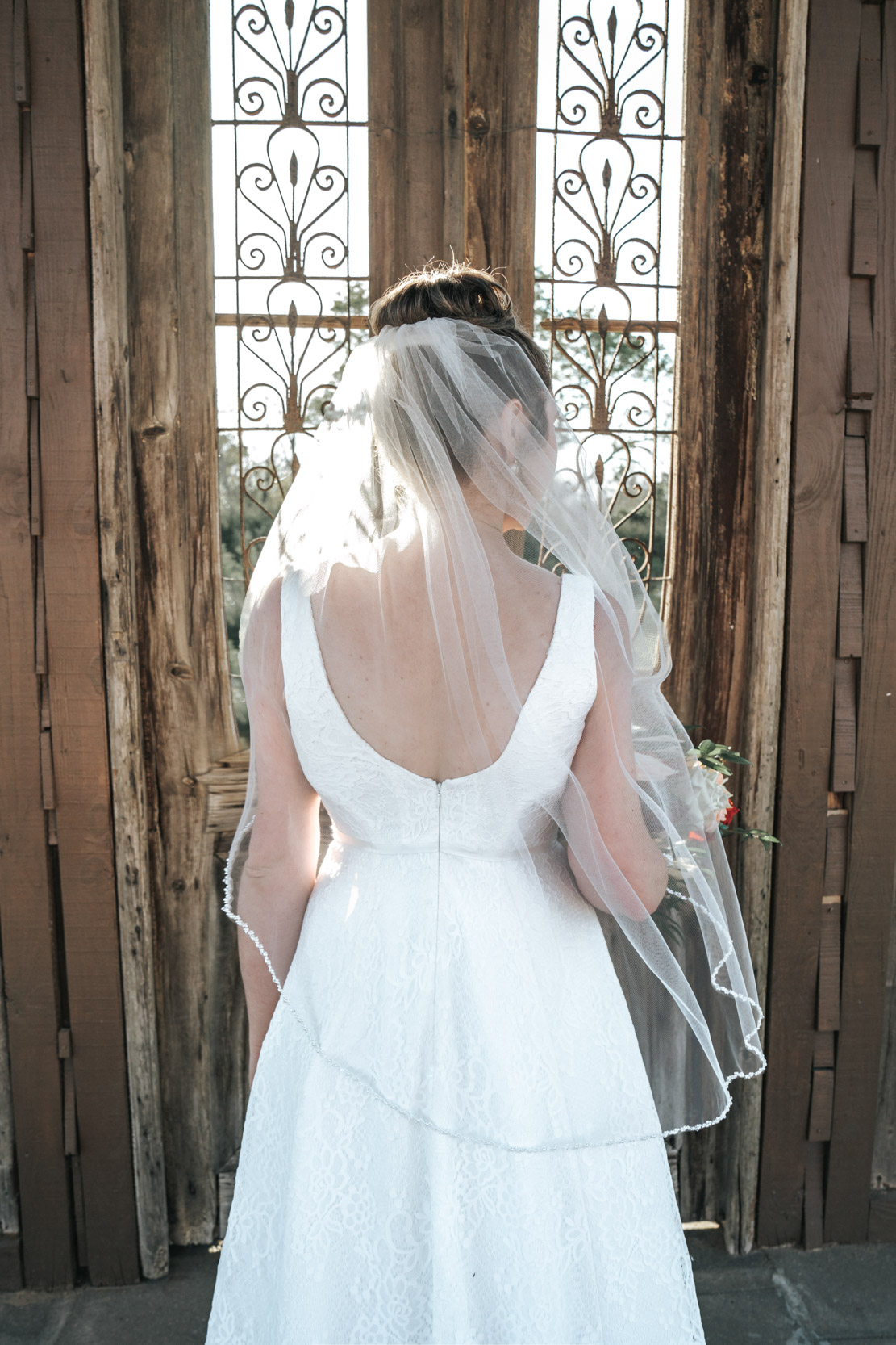 back of bride and her veil in front of rustic windows at Berry Barn in Amite, Louisiana
