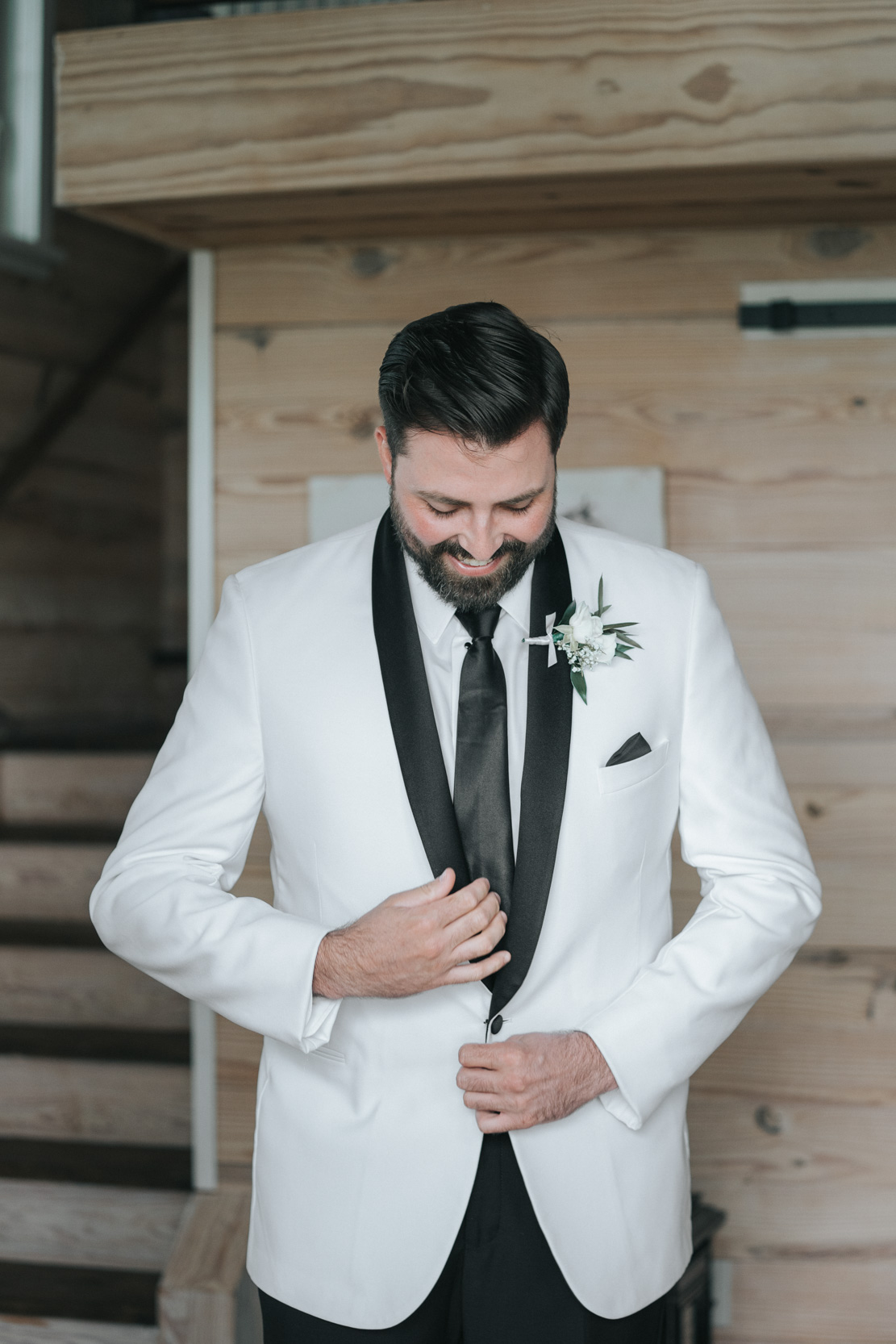 groom buttoning his jacket and smiling on his wedding day at White Magnolia in Louisiana