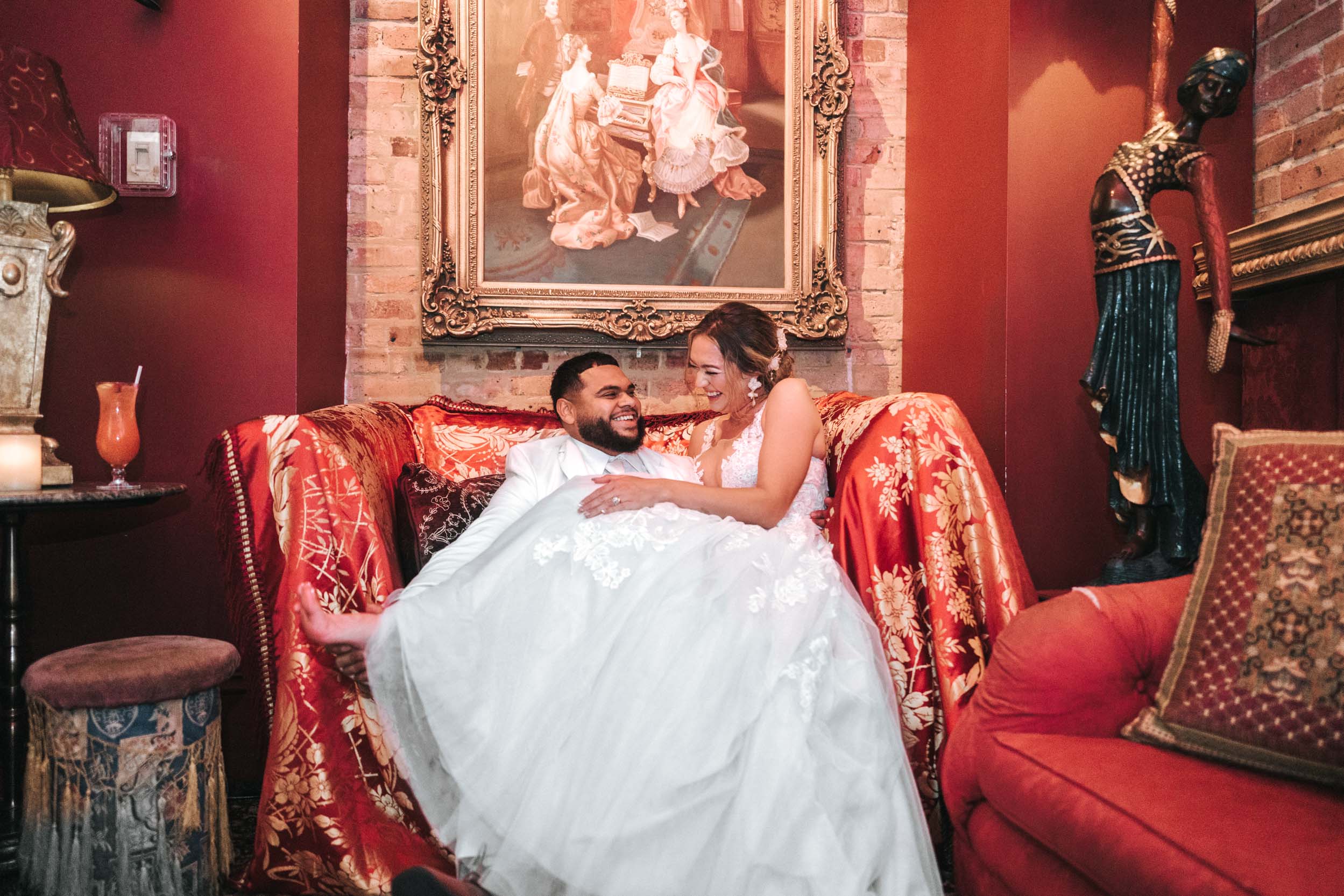 Bride and Groom laughing on red chair at Muriel’s Jackson Square in New Orleans