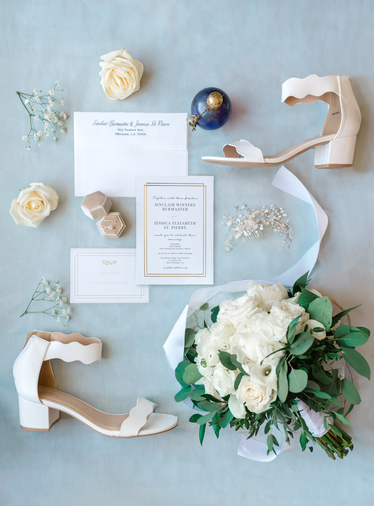 wedding flat lay of bridal shoes, flowers, invitation, and rings