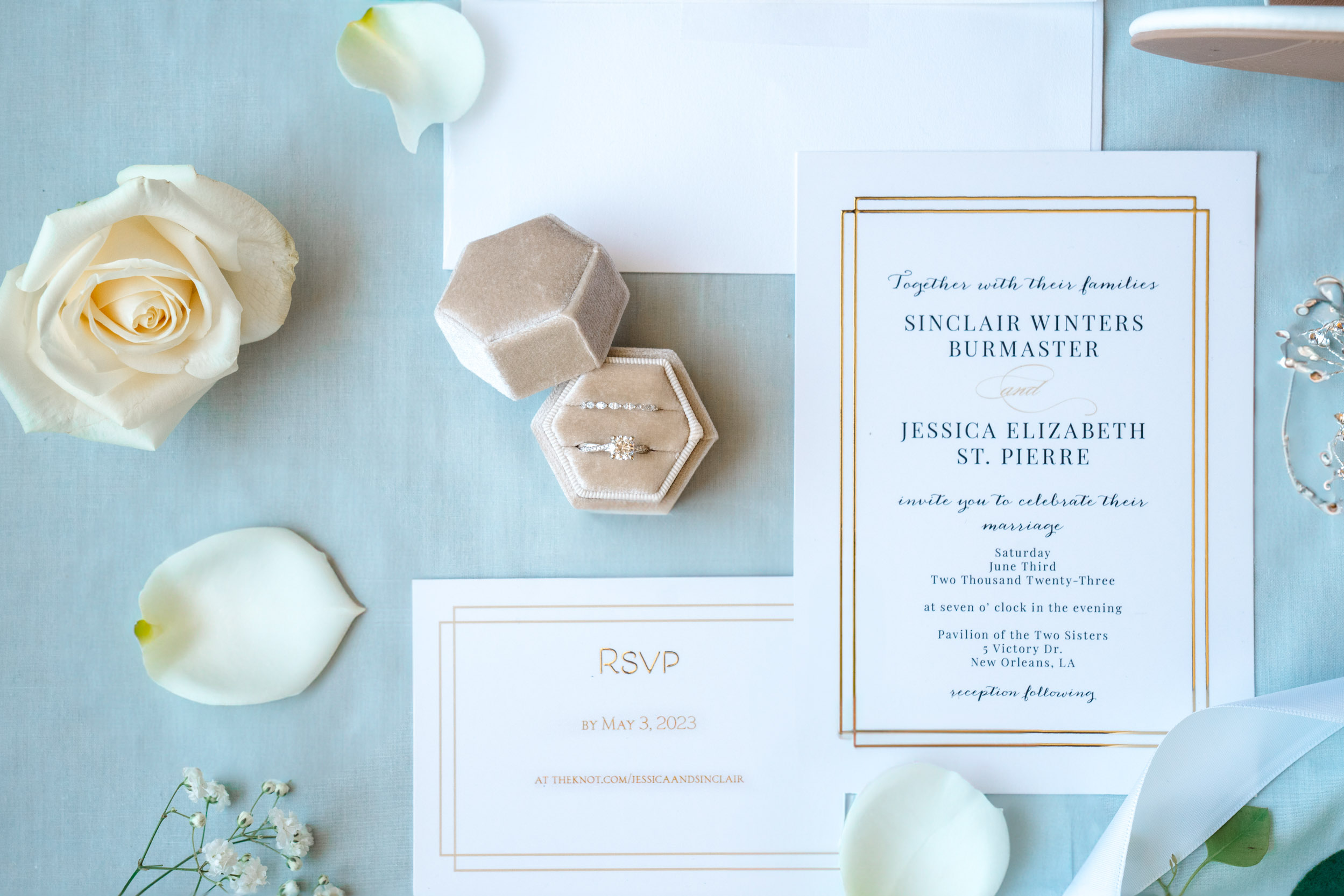 wedding flat lay of rings, invitations, rose pedals