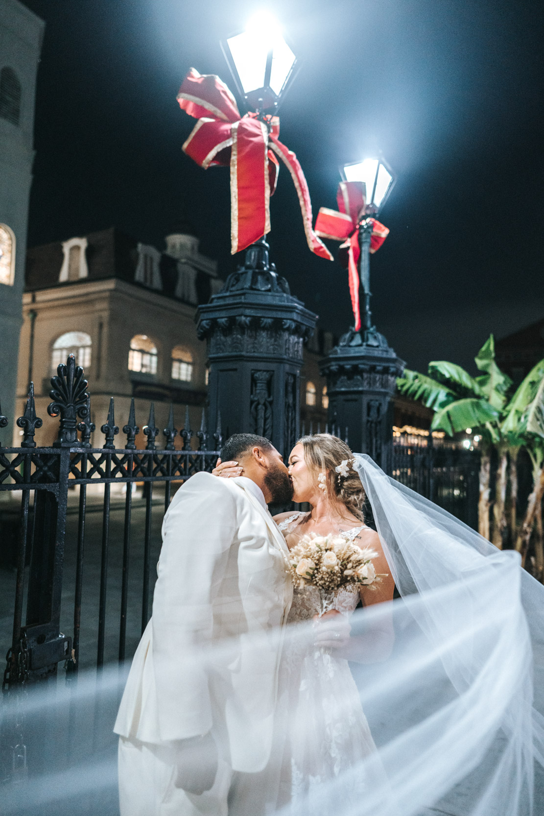 Bridal veil flying in the air and kissing groom at Jackson Square in New Orleans