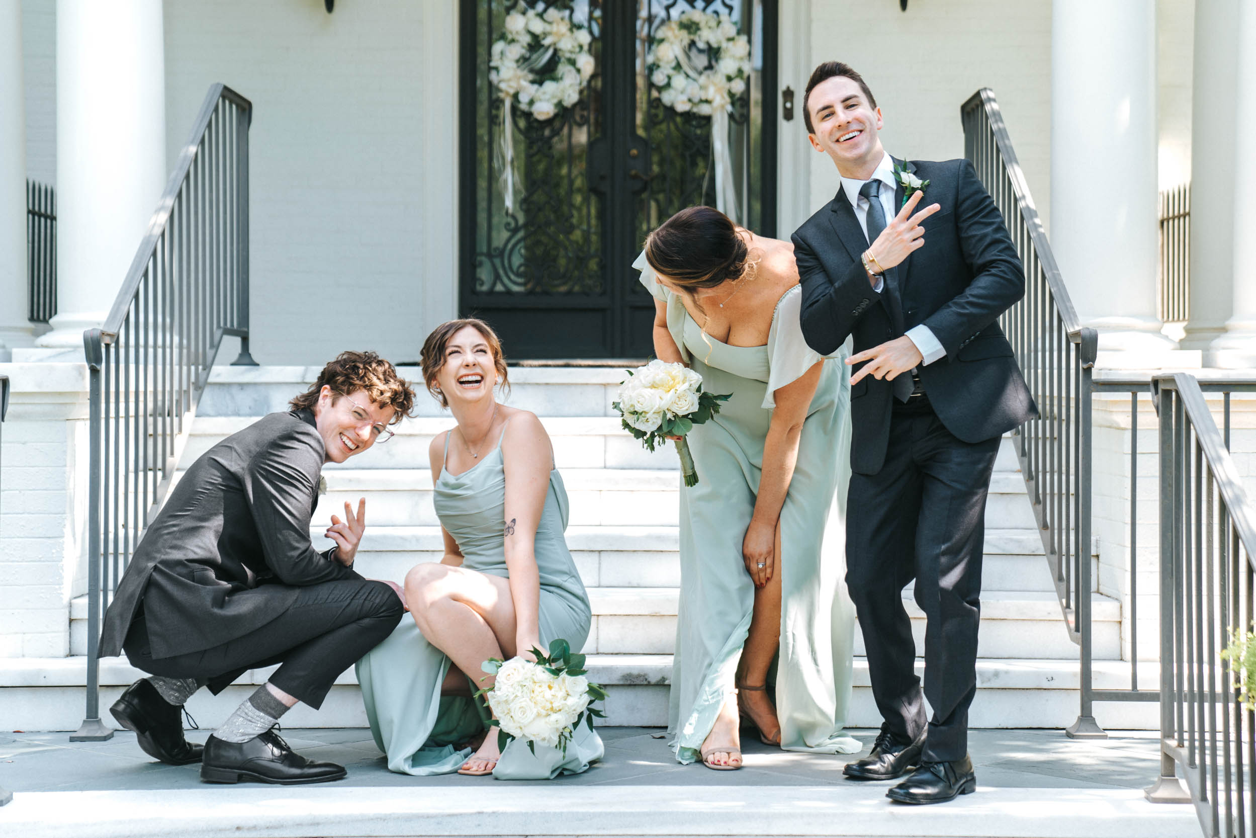 Wedding party laughing on steps in front of uptown mansion in New Orleans